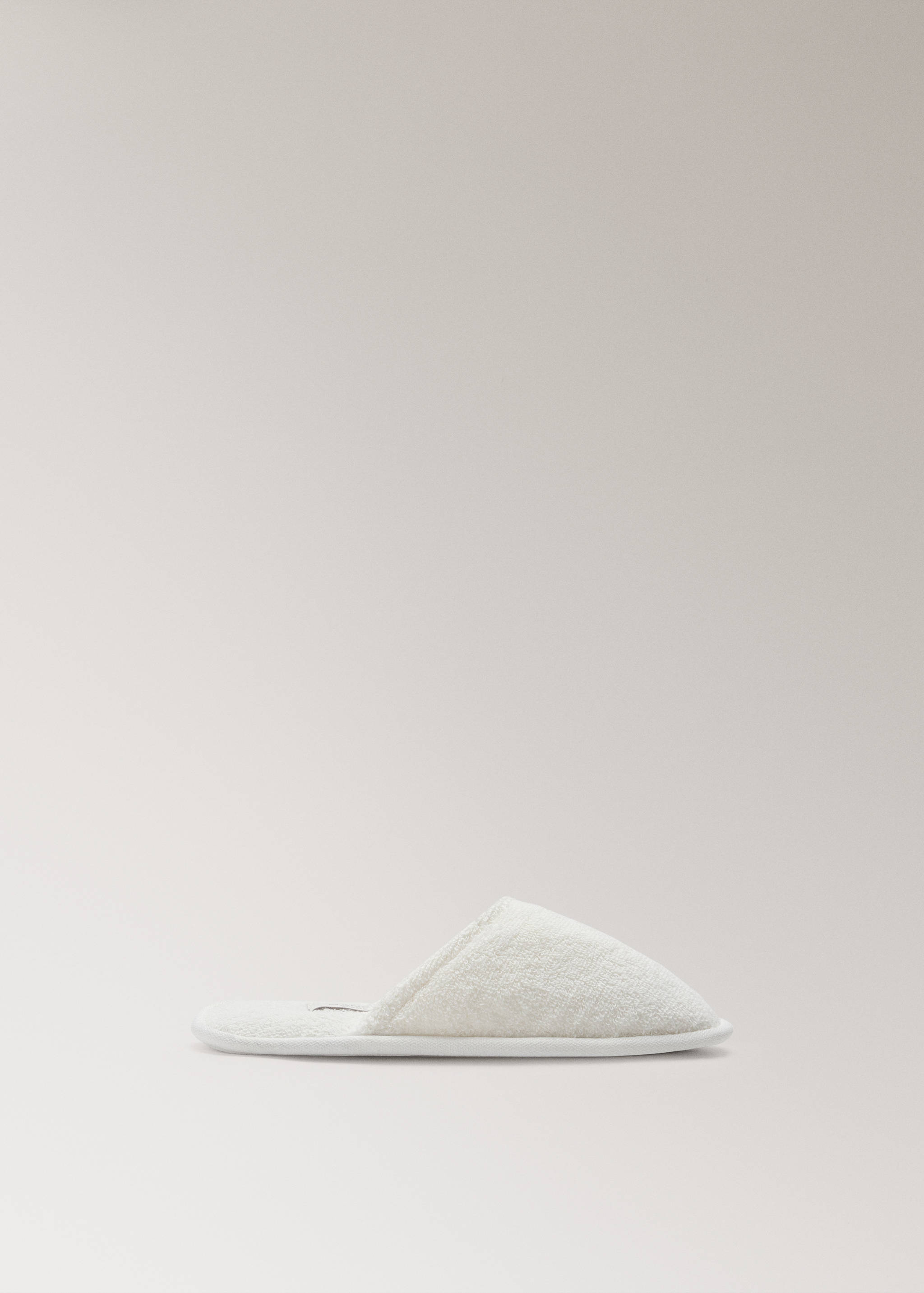 Off-white bathroom slippers in textured towelling fabric.