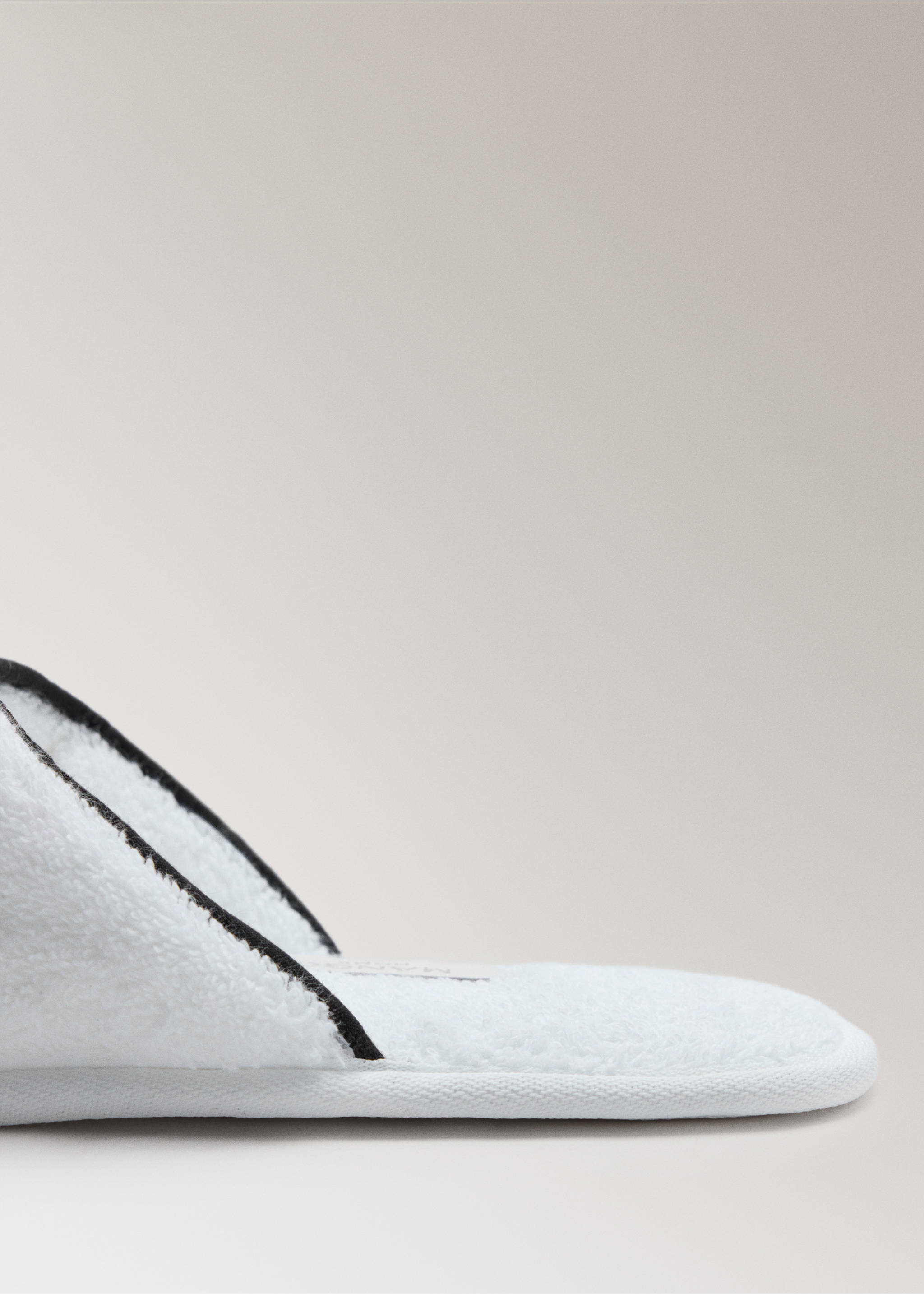 Primer plano de una zapatilla de baño blanca con ribete negro en contraste., Blanco. Ref: 37072957-00.