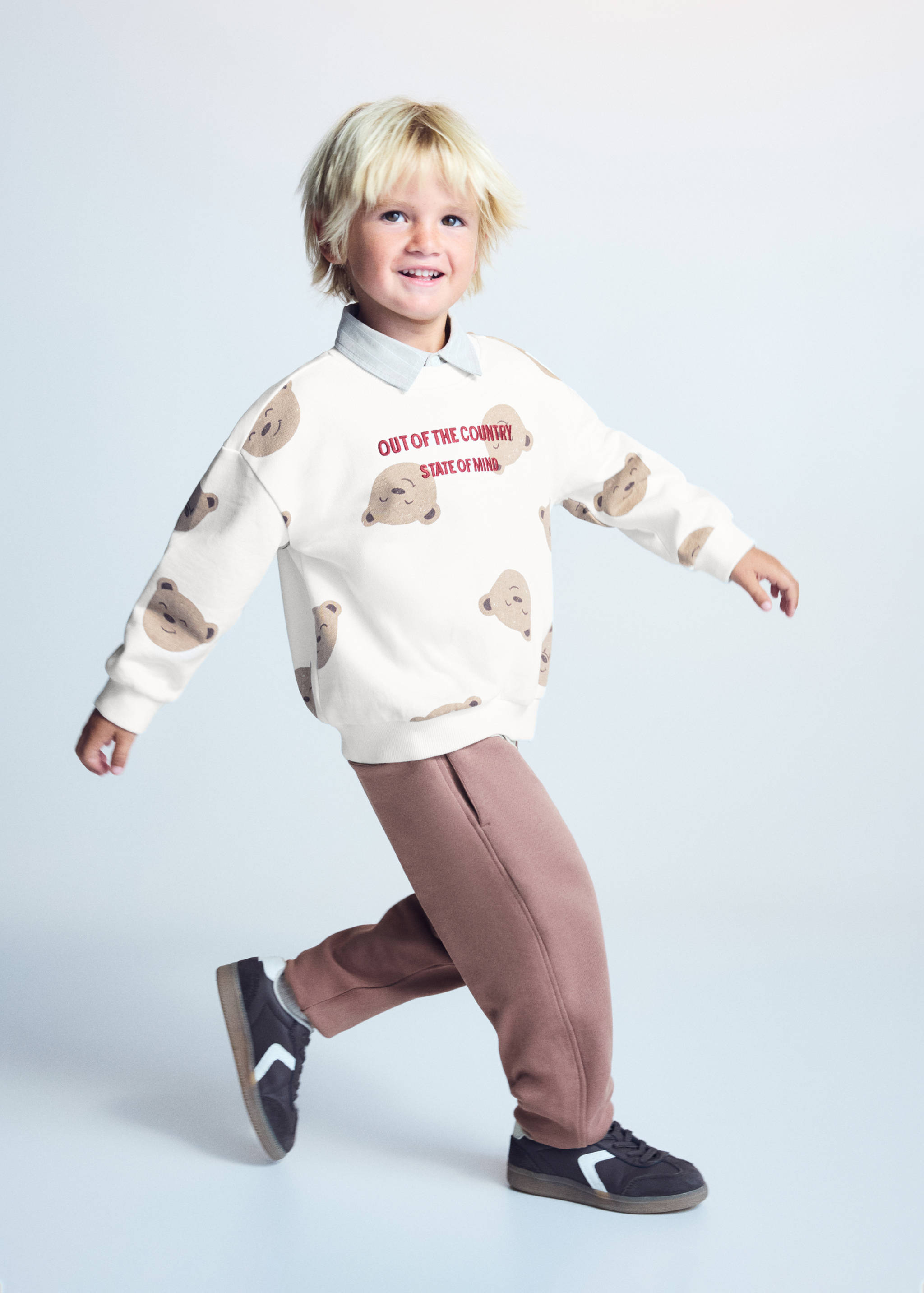 Brown trousers worn with a bear-print sweatshirt.