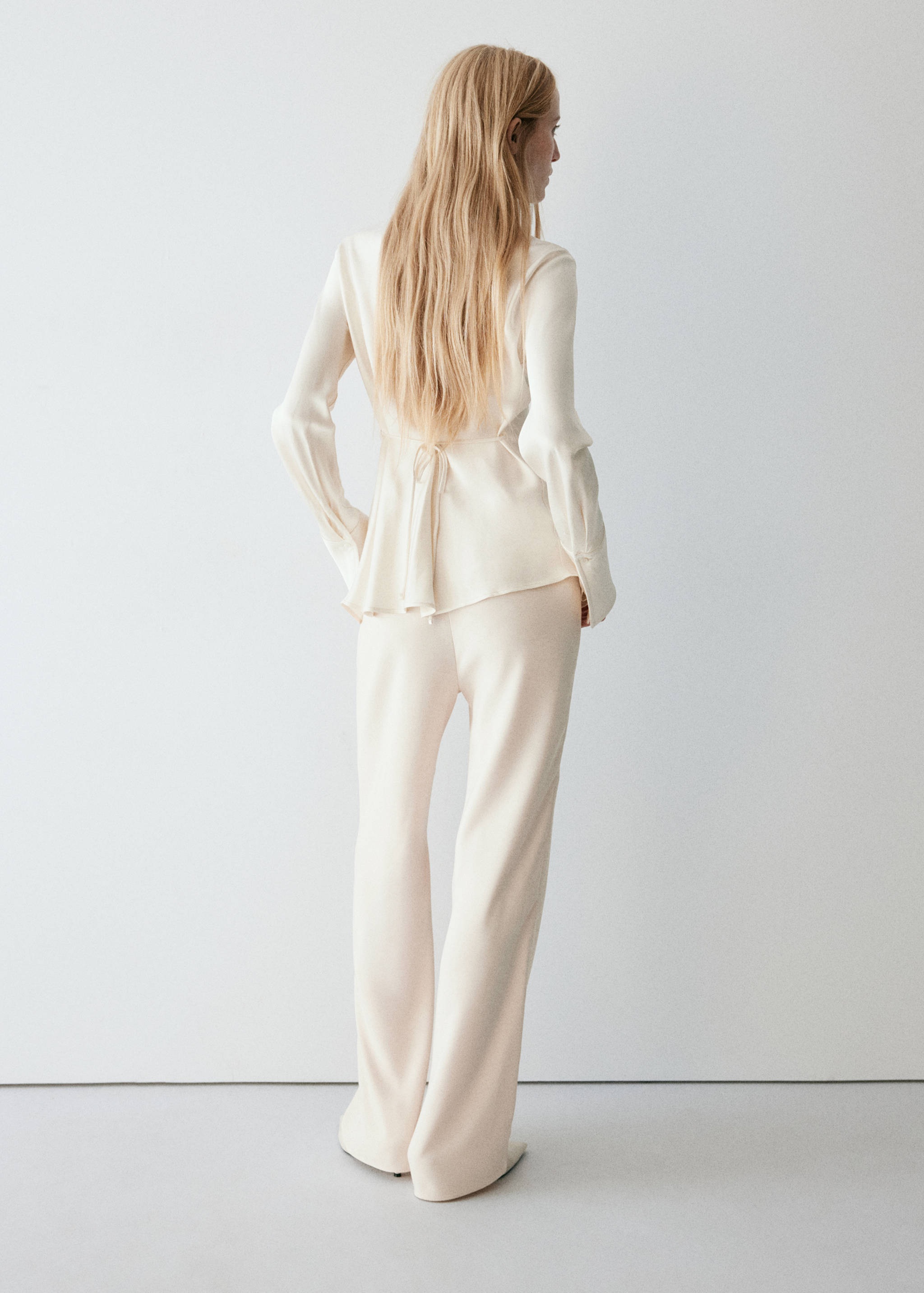 Cream trousers, shown from the back with a matching cream top.