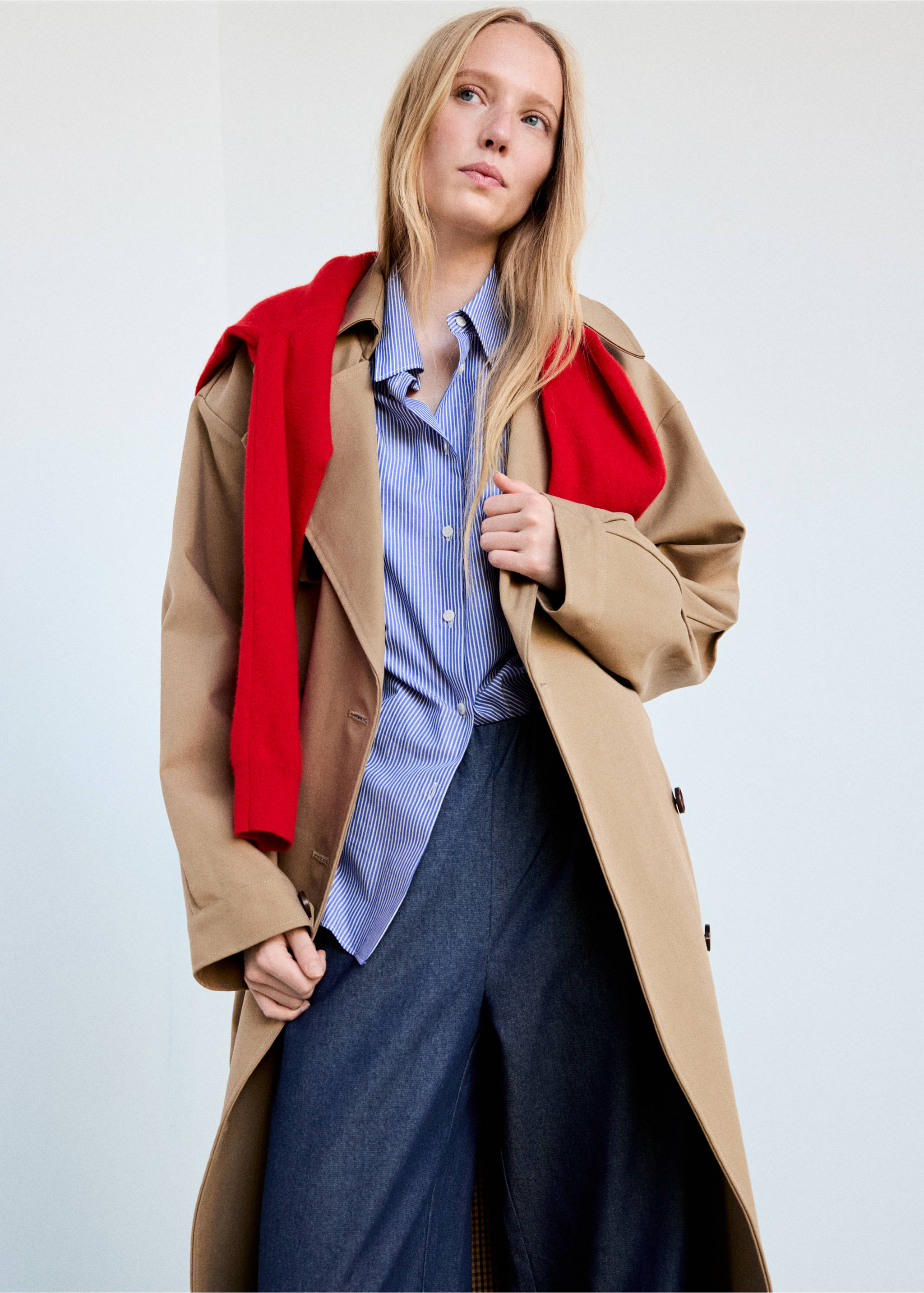Dark blue trousers worn with a striped shirt, trench coat and red sweater., Blue. Ref: 37074471-01.