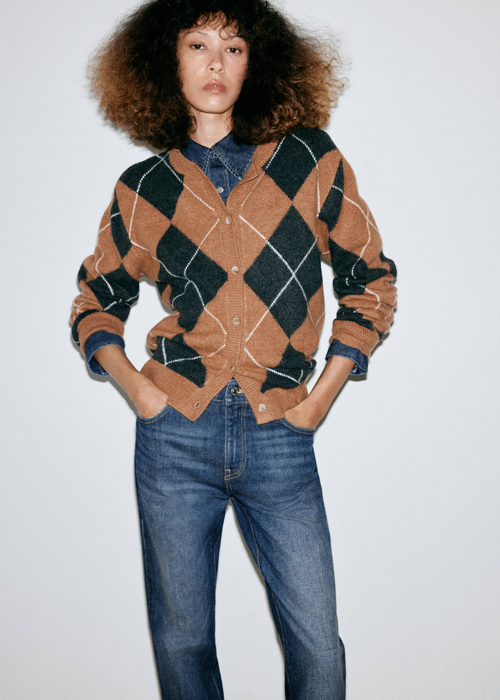 Brown and dark green argyle cardigan worn with a denim shirt and trousers.