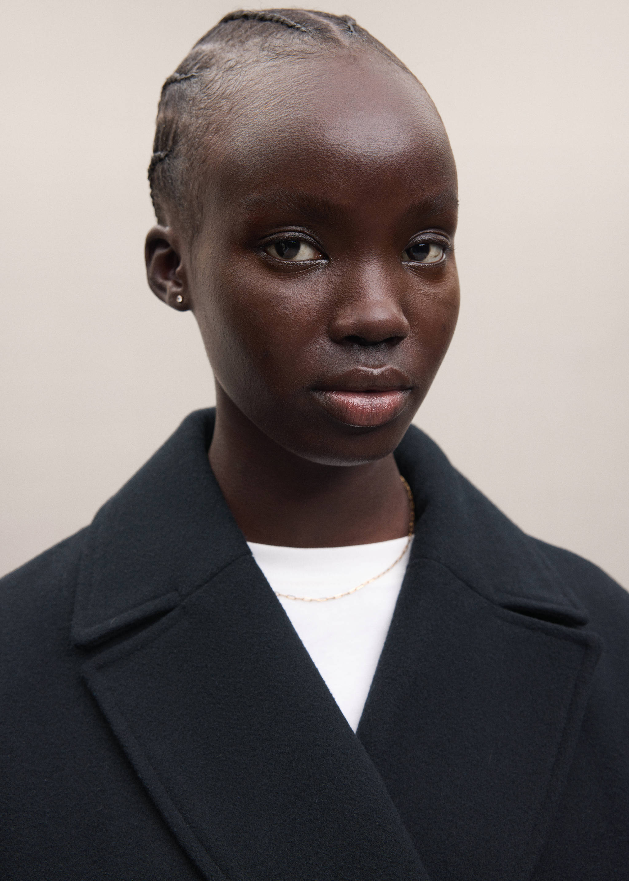 Close-up of a dark coat with wide lapels worn over a white top.