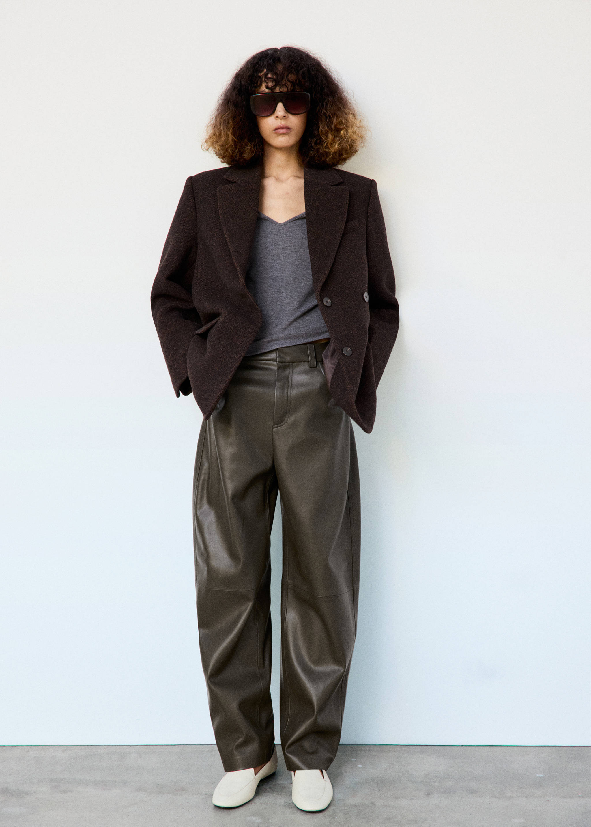 Dark olive green trousers worn with a grey top and dark brown blazer.