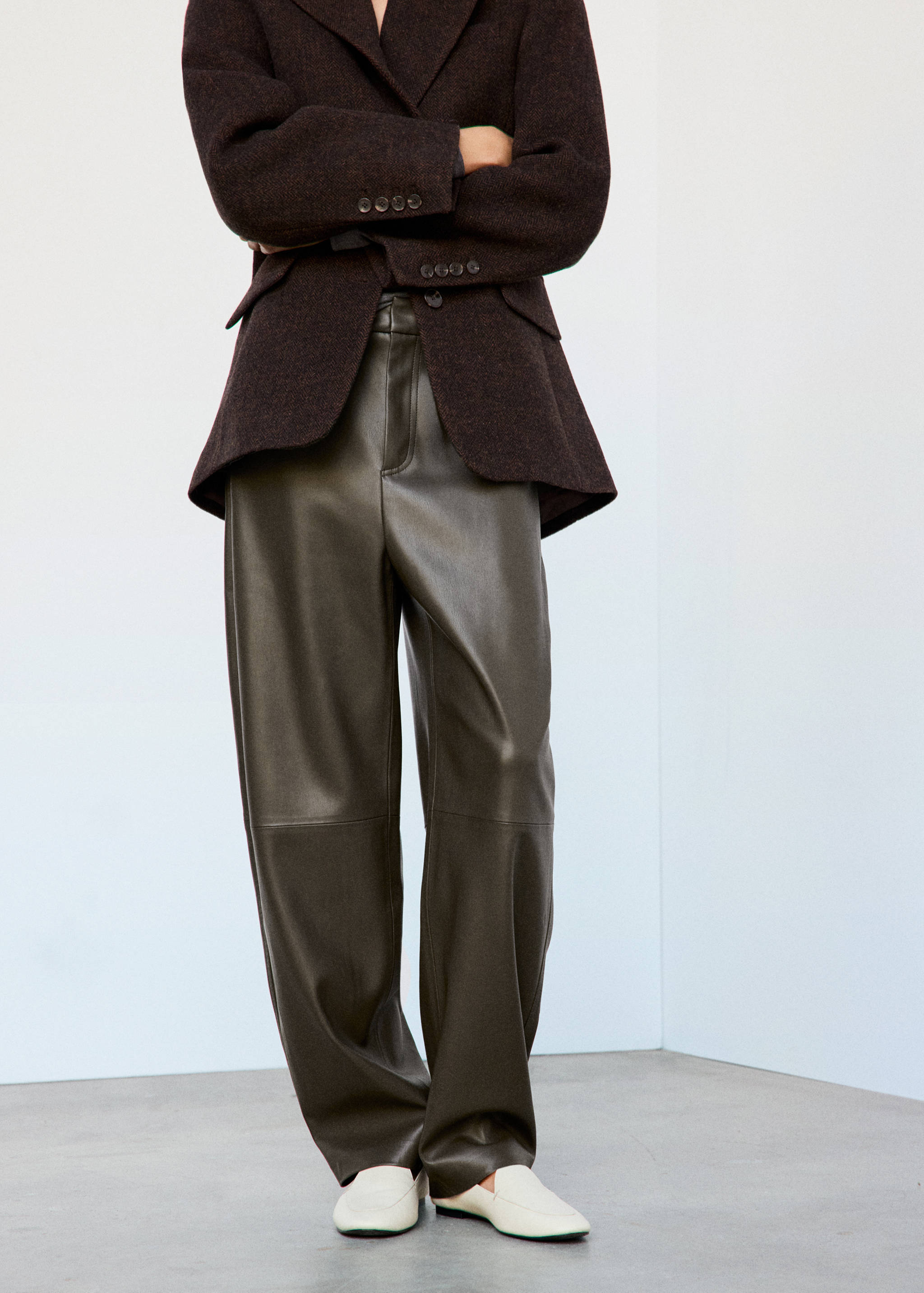 Olive green faux-leather trousers worn with a dark brown blazer.