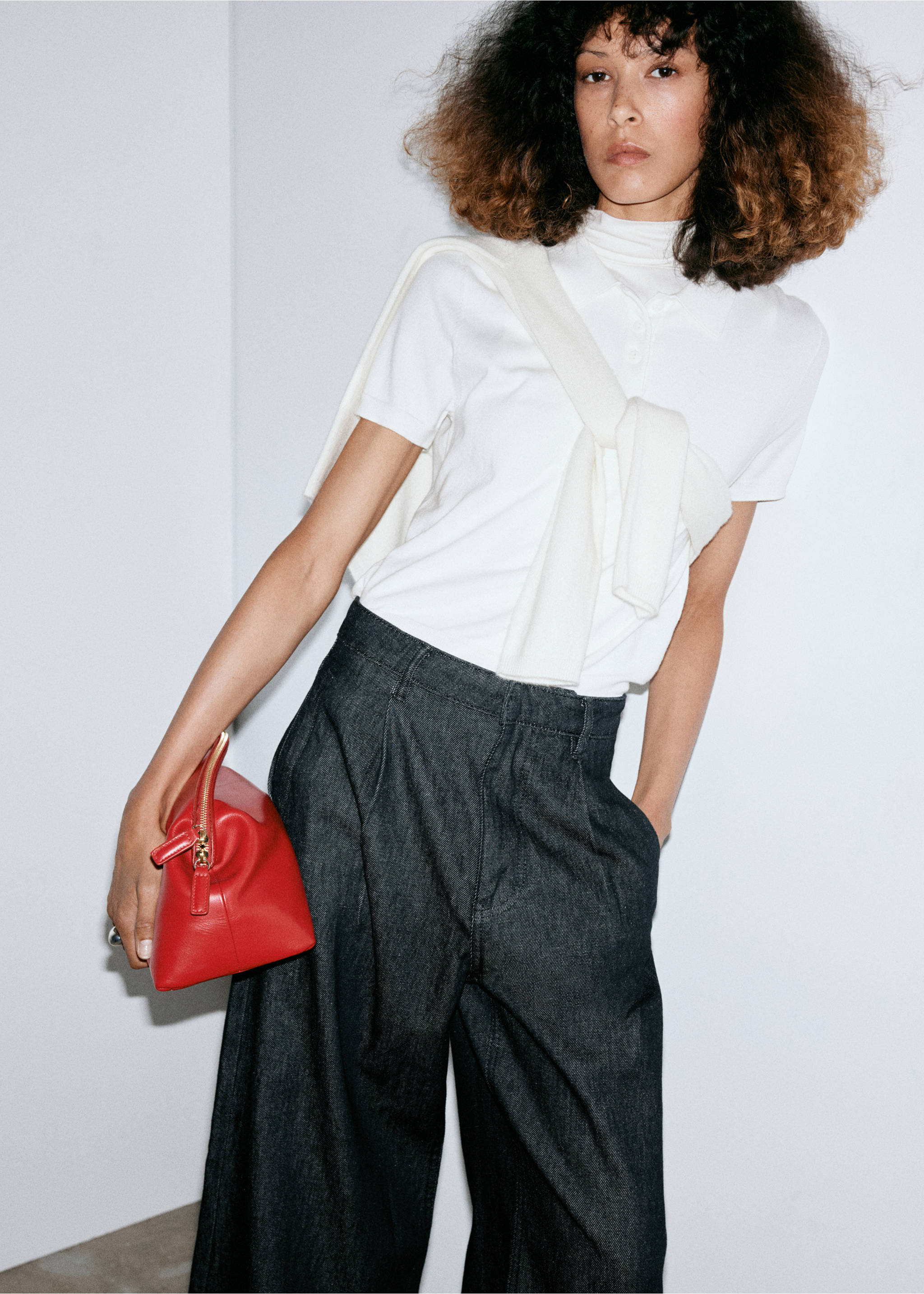 Dark grey pleated wide-leg trousers worn with a white polo shirt and a red handbag., Black. Ref: 37076748-00.