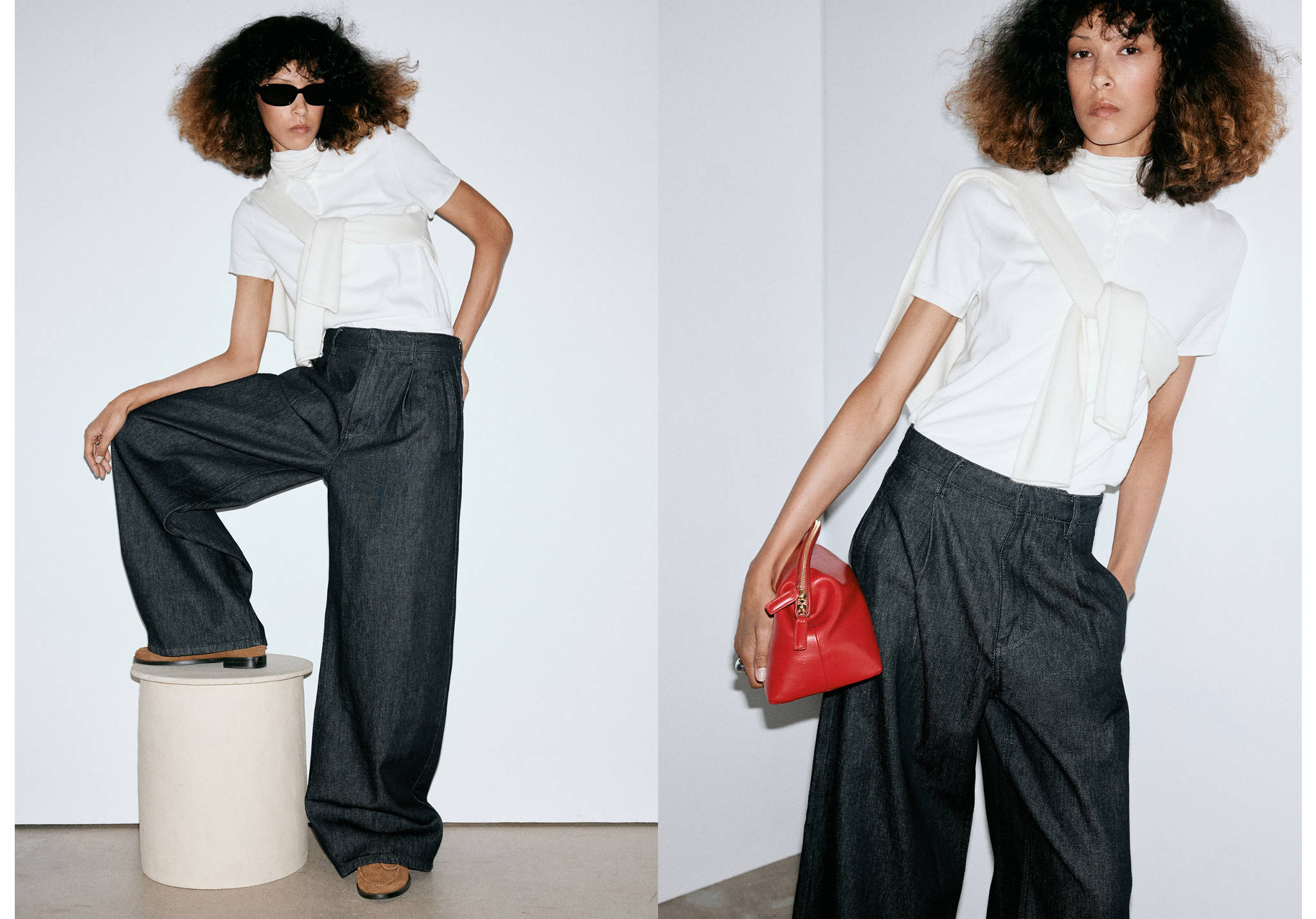 Dark wide-leg denim trousers with pleats, worn with a white polo shirt and a sweater tied over shoulders.