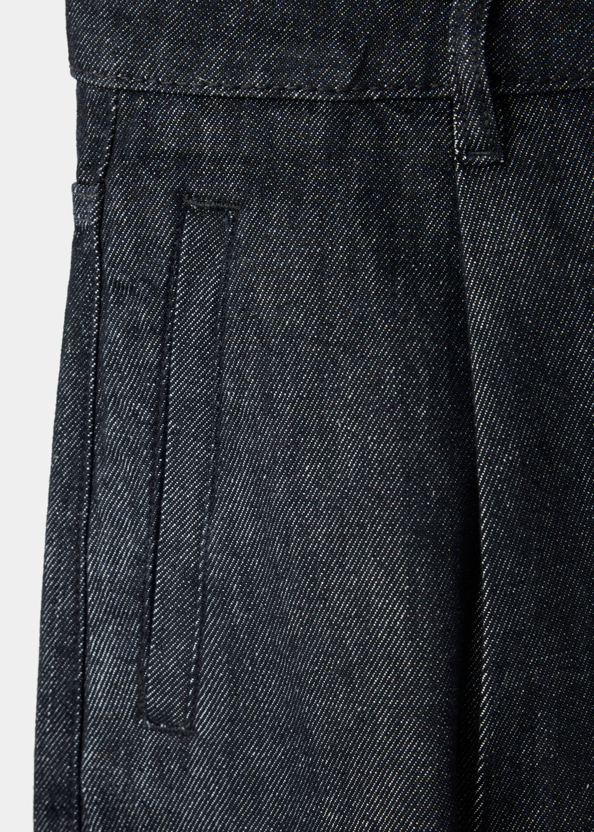 Close-up of dark denim trousers showing pocket and waistband detail.