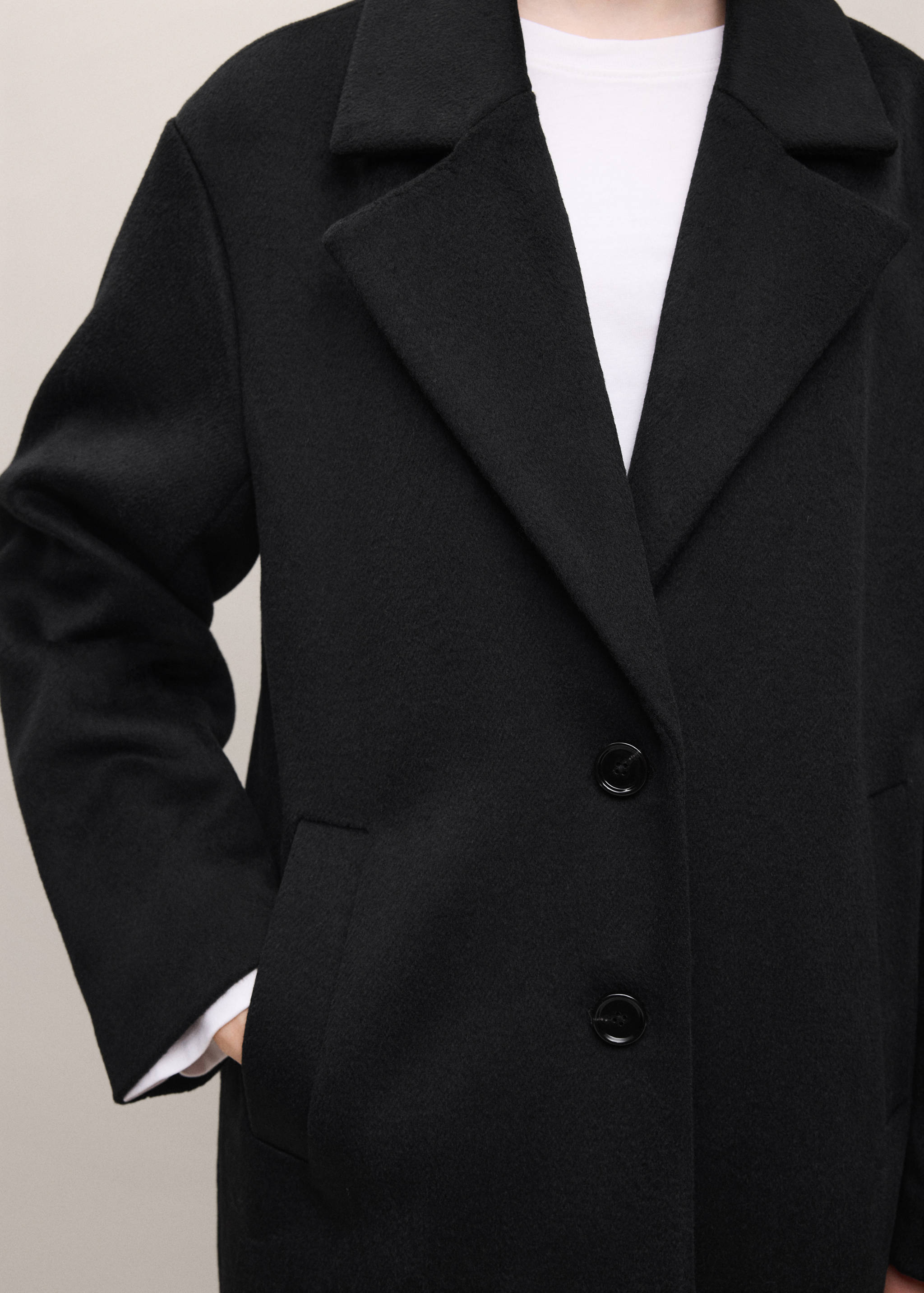 Close-up of a black coat with wide lapels and front buttons.