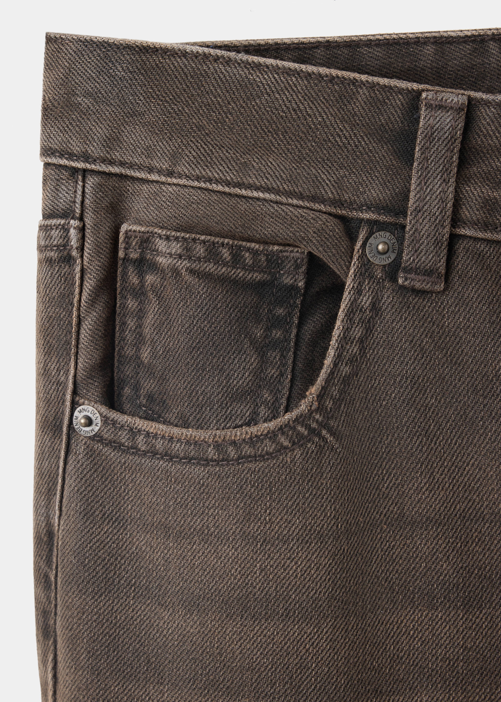 Close-up of brown denim trousers showing pocket and rivet details.