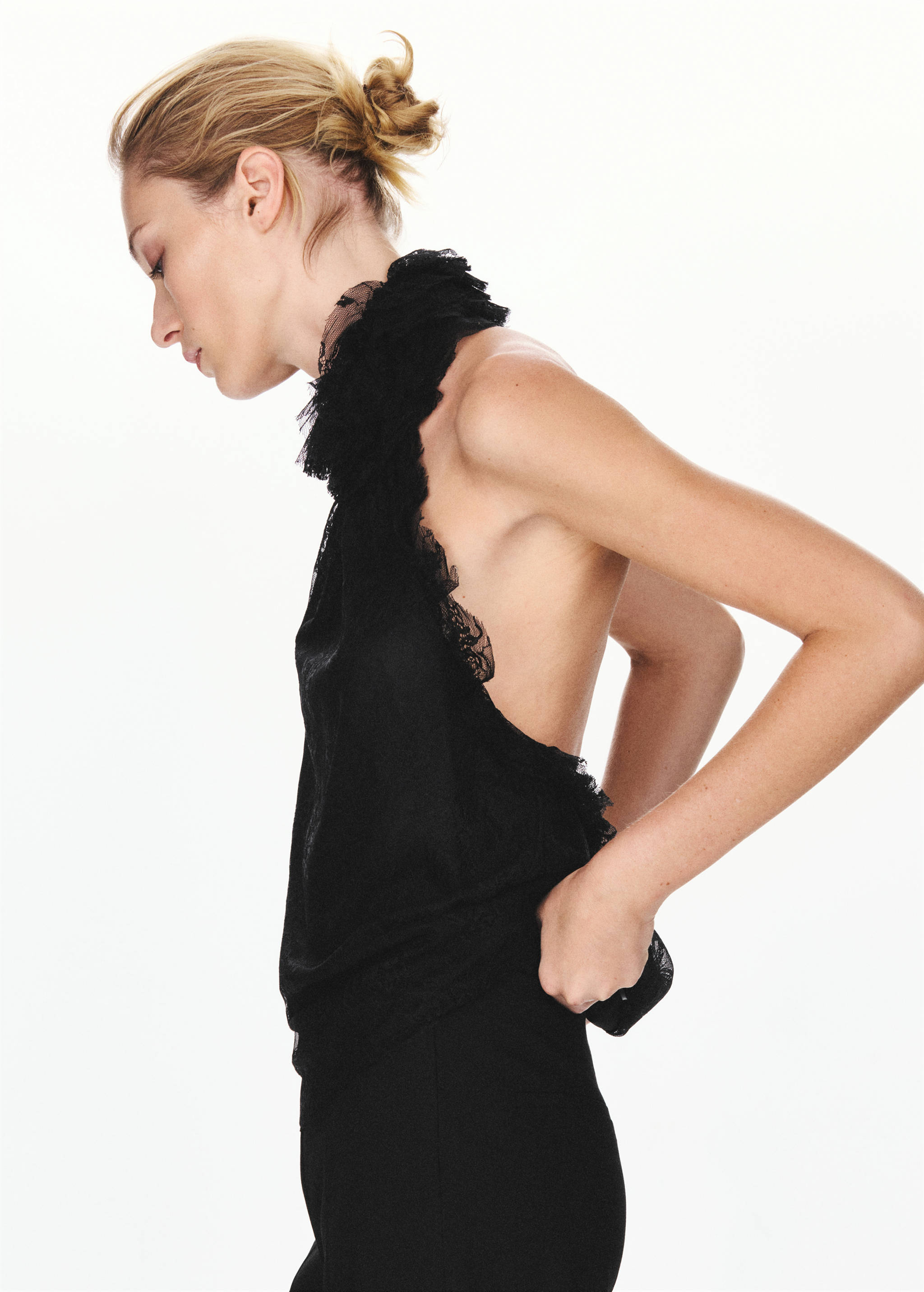 Black sleeveless top with high ruffled lace collar and open back.
