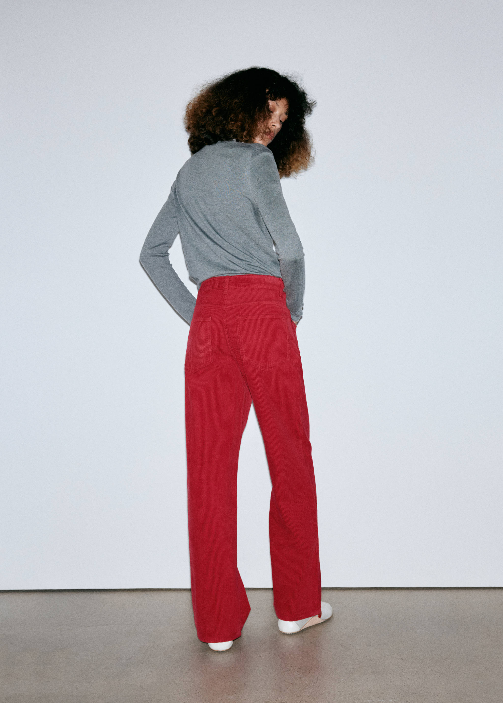 Back view of red denim trousers worn with a grey top.