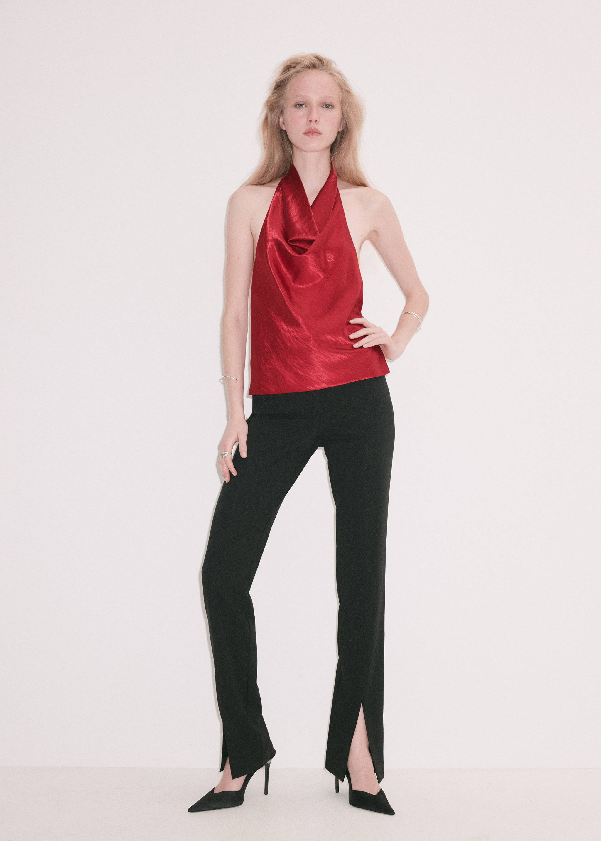 Red halter neck top with a draped cowl neckline, worn with black trousers.