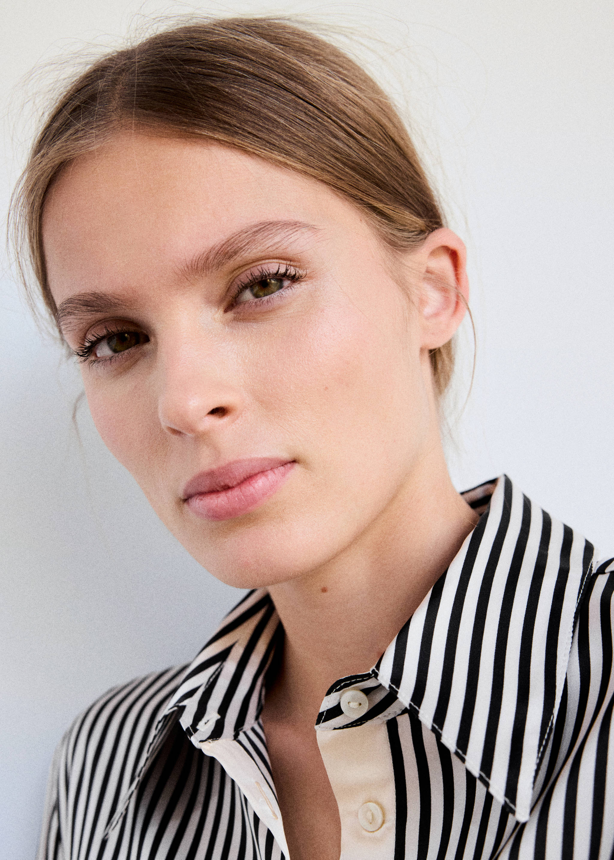 Close-up of a model wearing a black and white striped shirt with a pointed collar.
