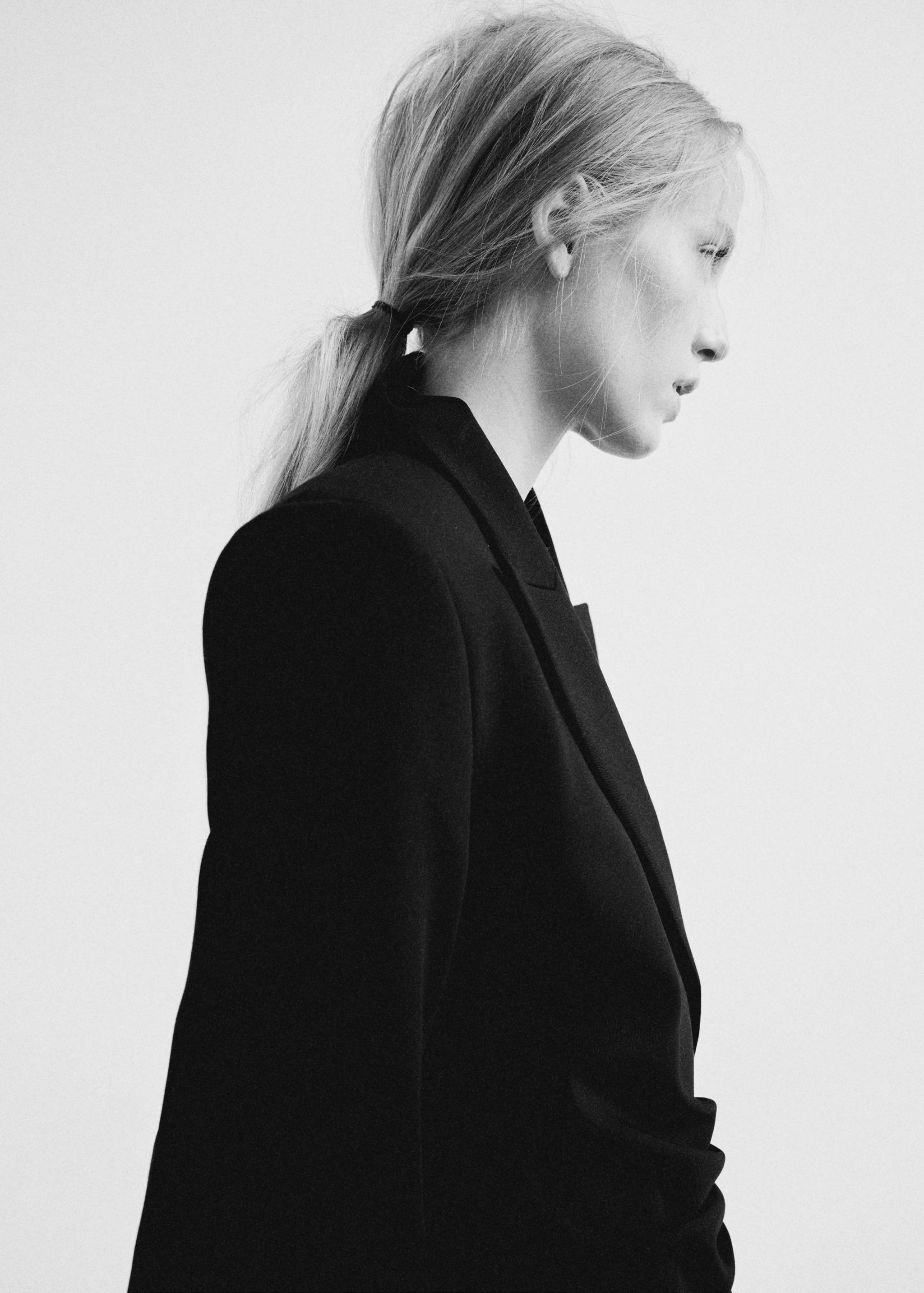 Close-up of a model wearing a black dress with a lapel collar.