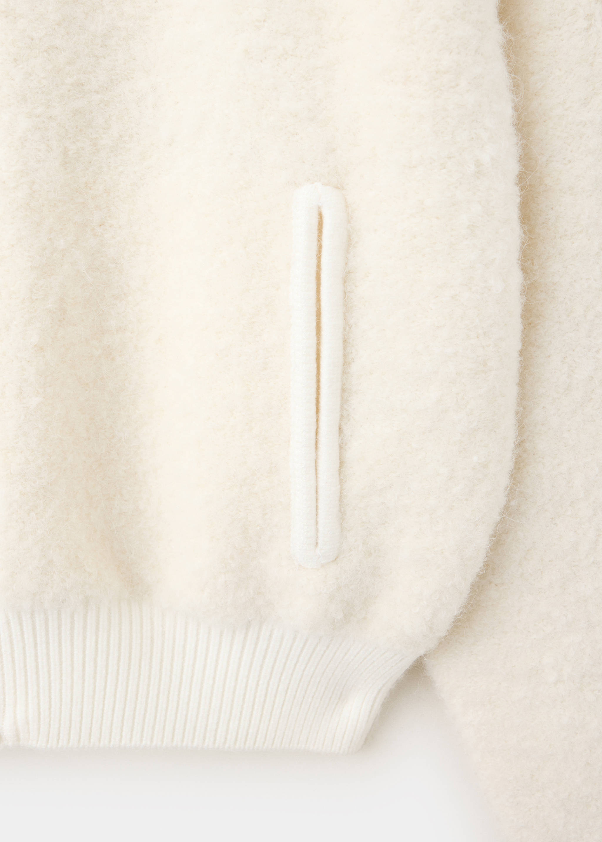 Close-up of an off-white textured jacket showing a vertical welt pocket.