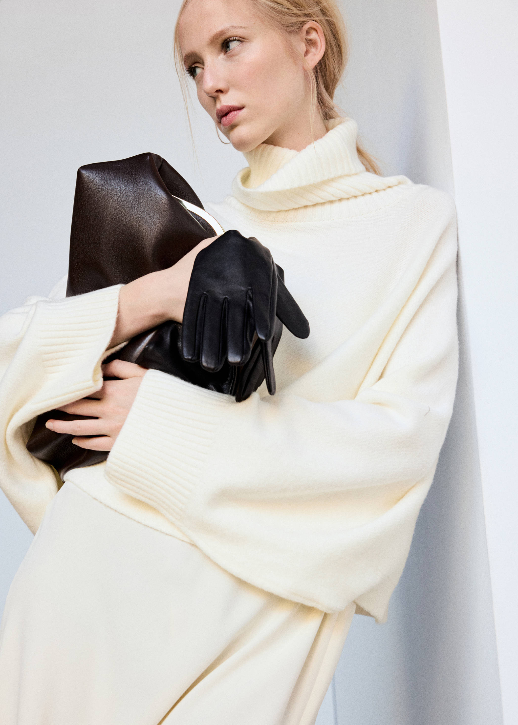 Off-white cape with a ribbed turtleneck and wide sleeves.