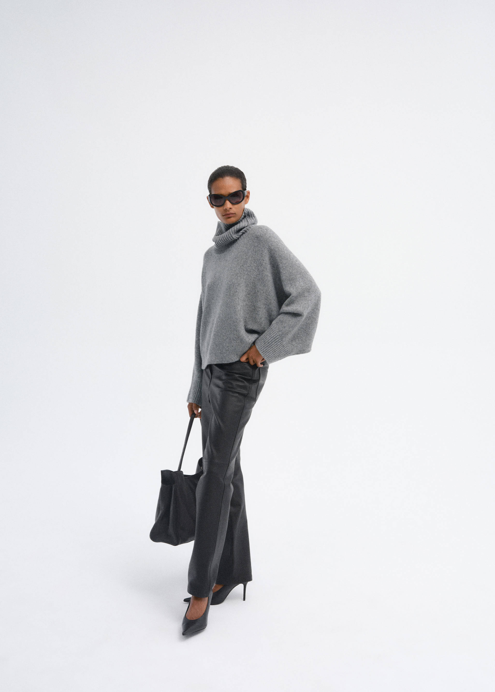 Grey knitted roll-neck poncho worn with black trousers and heels