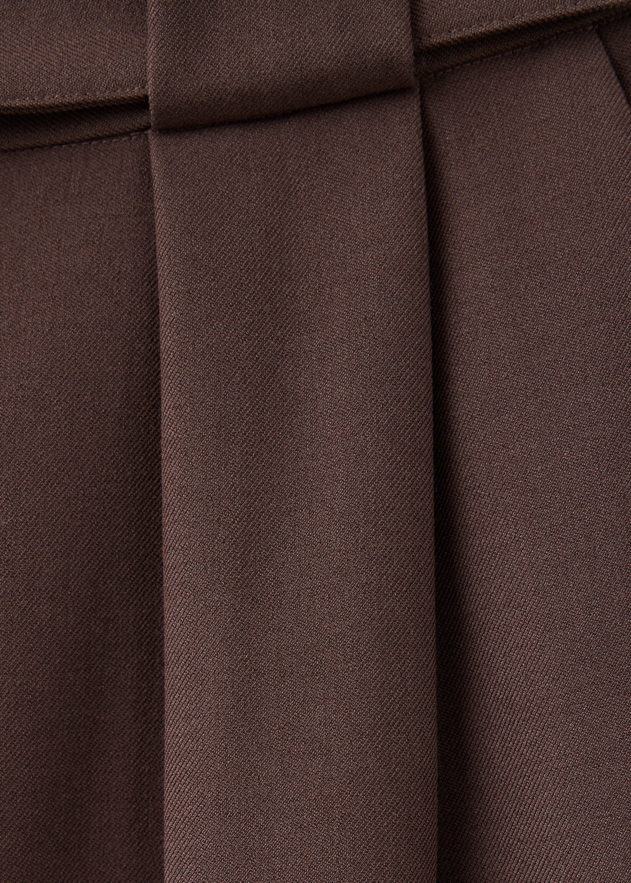 Brown trousers fabric and pleat detail.