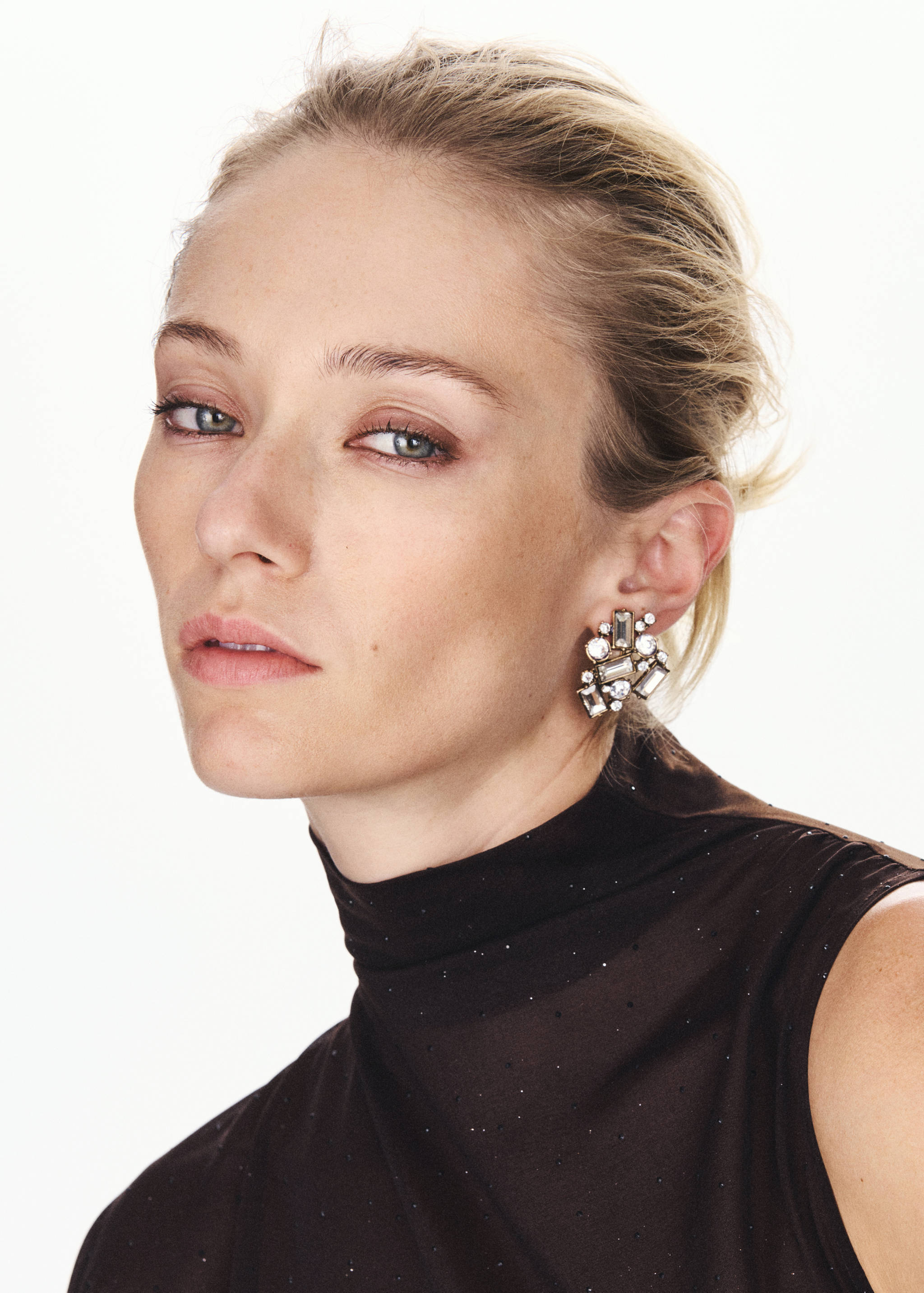 Close-up of a dark brown sleeveless high-neck top with subtle glitter detail on a model.
