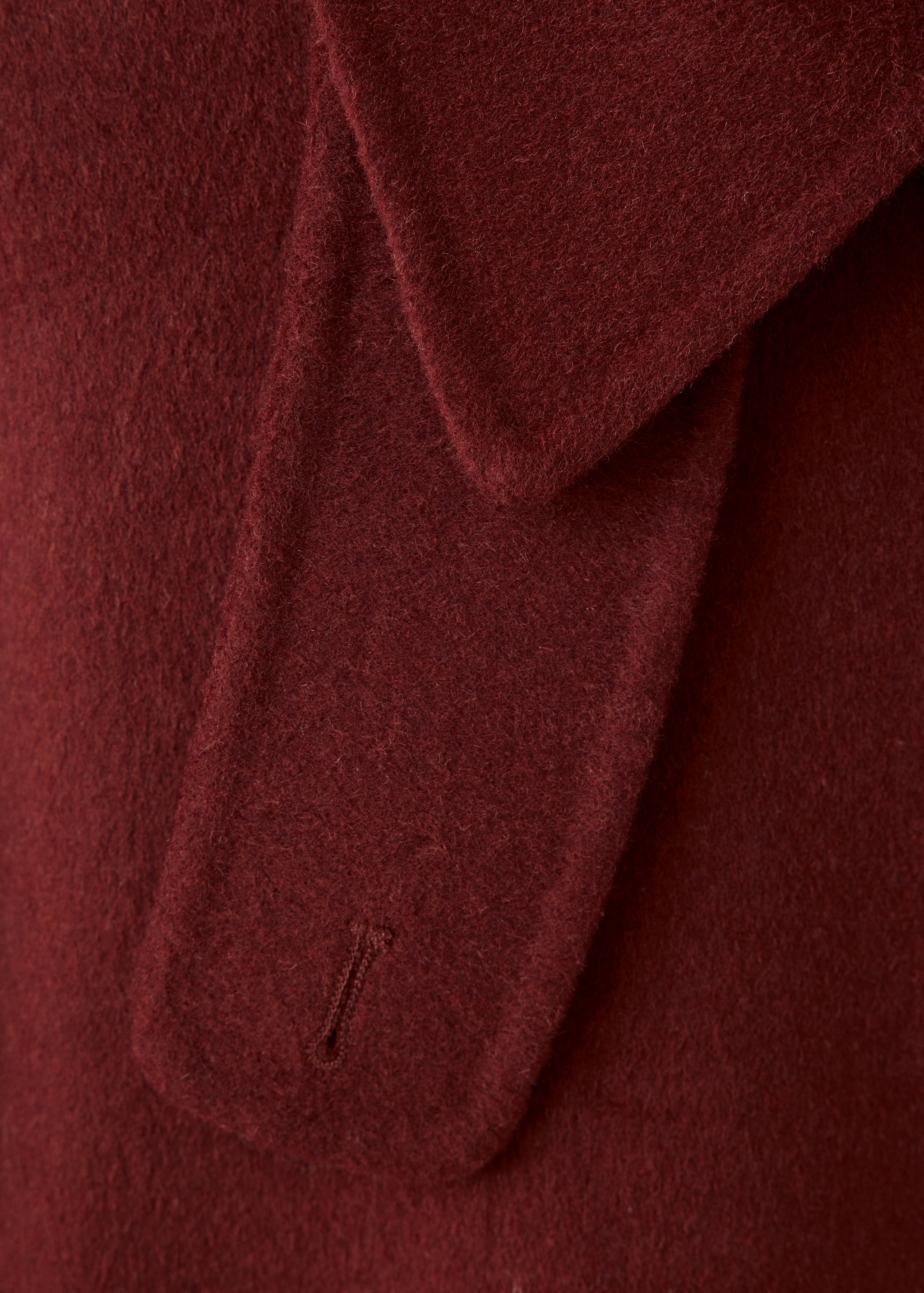 Close-up of a dark burgundy jacket lapel and button tab.