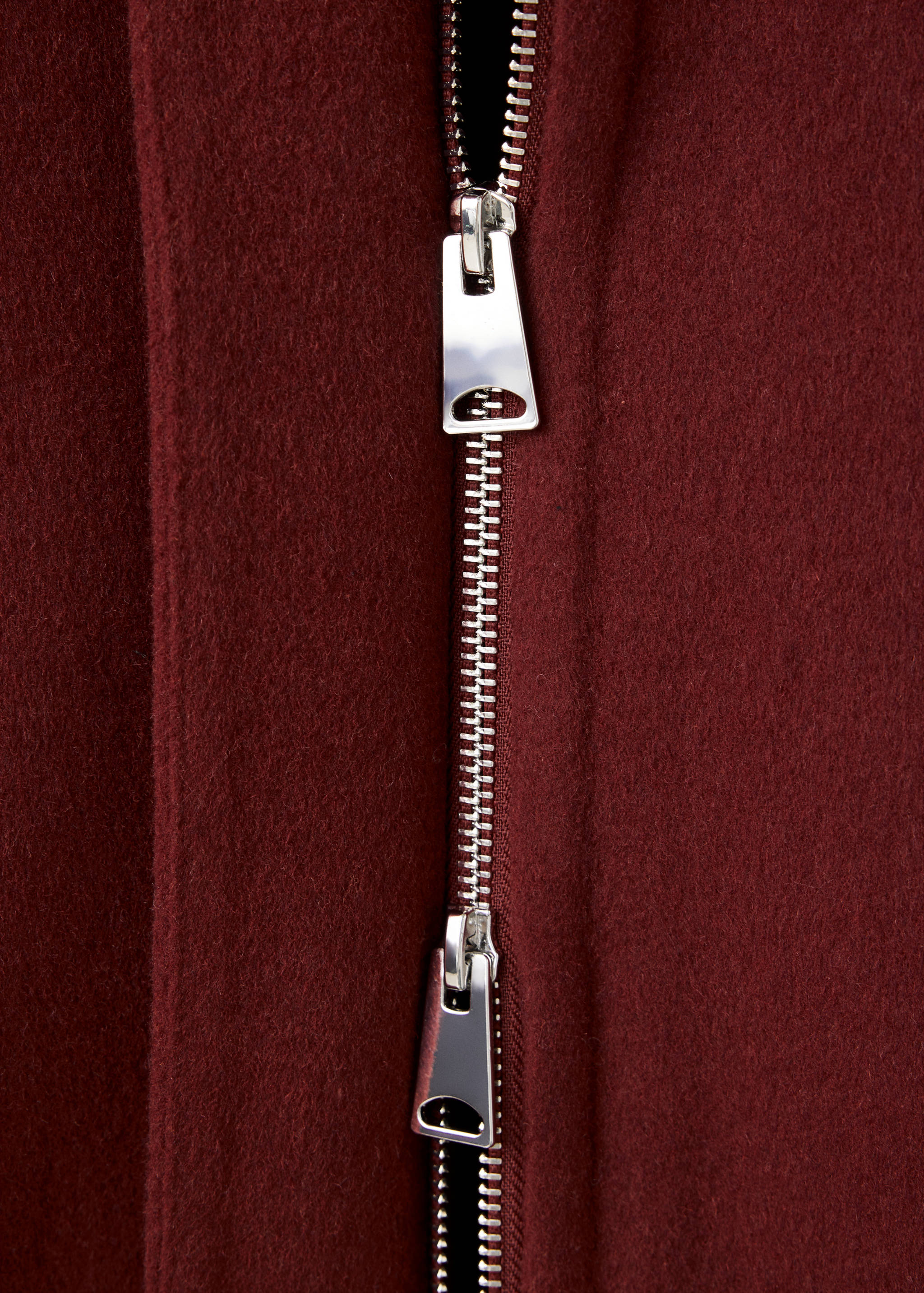 Close-up of a burgundy jacket zipper and textured fabric detail.