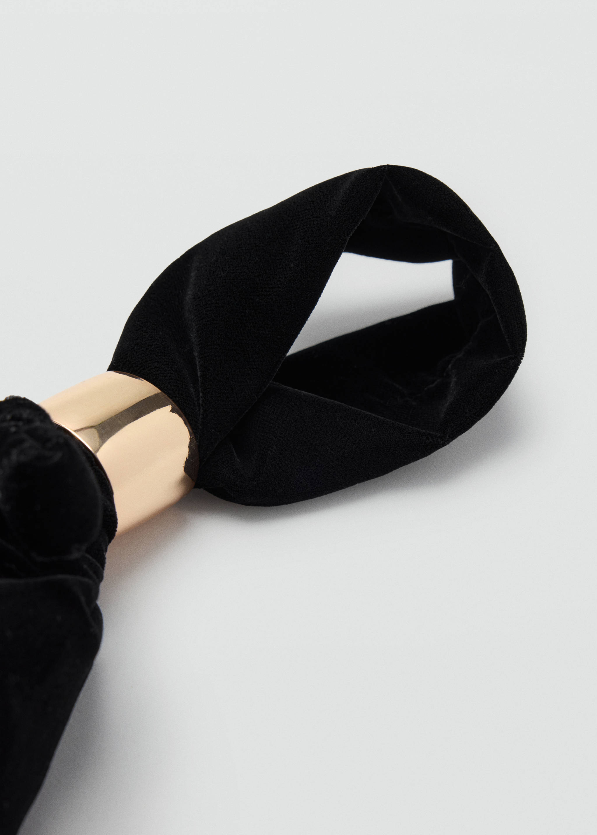 Close-up of a black velvet handbag handle with a metallic gold-tone accent.