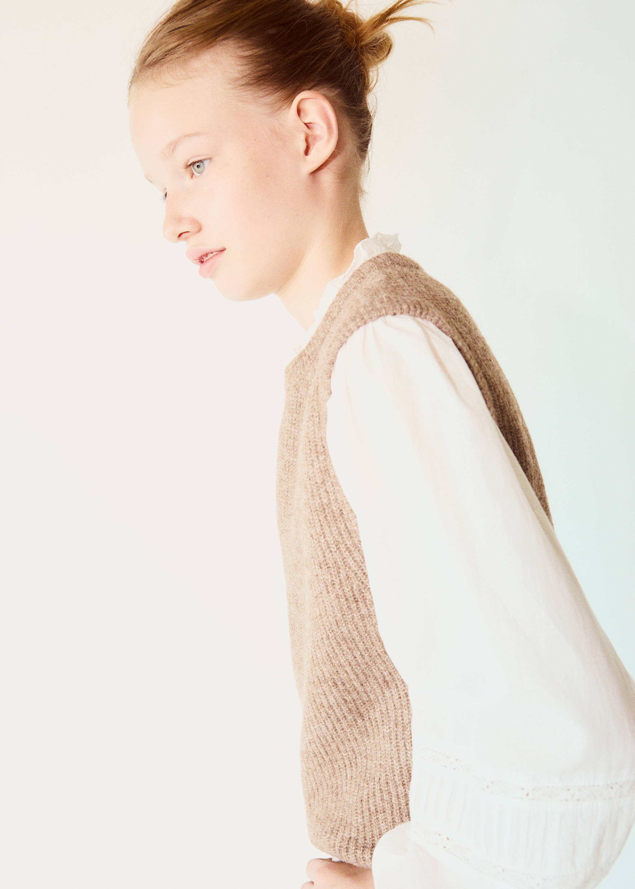 Brown knit vest layered over a white blouse.