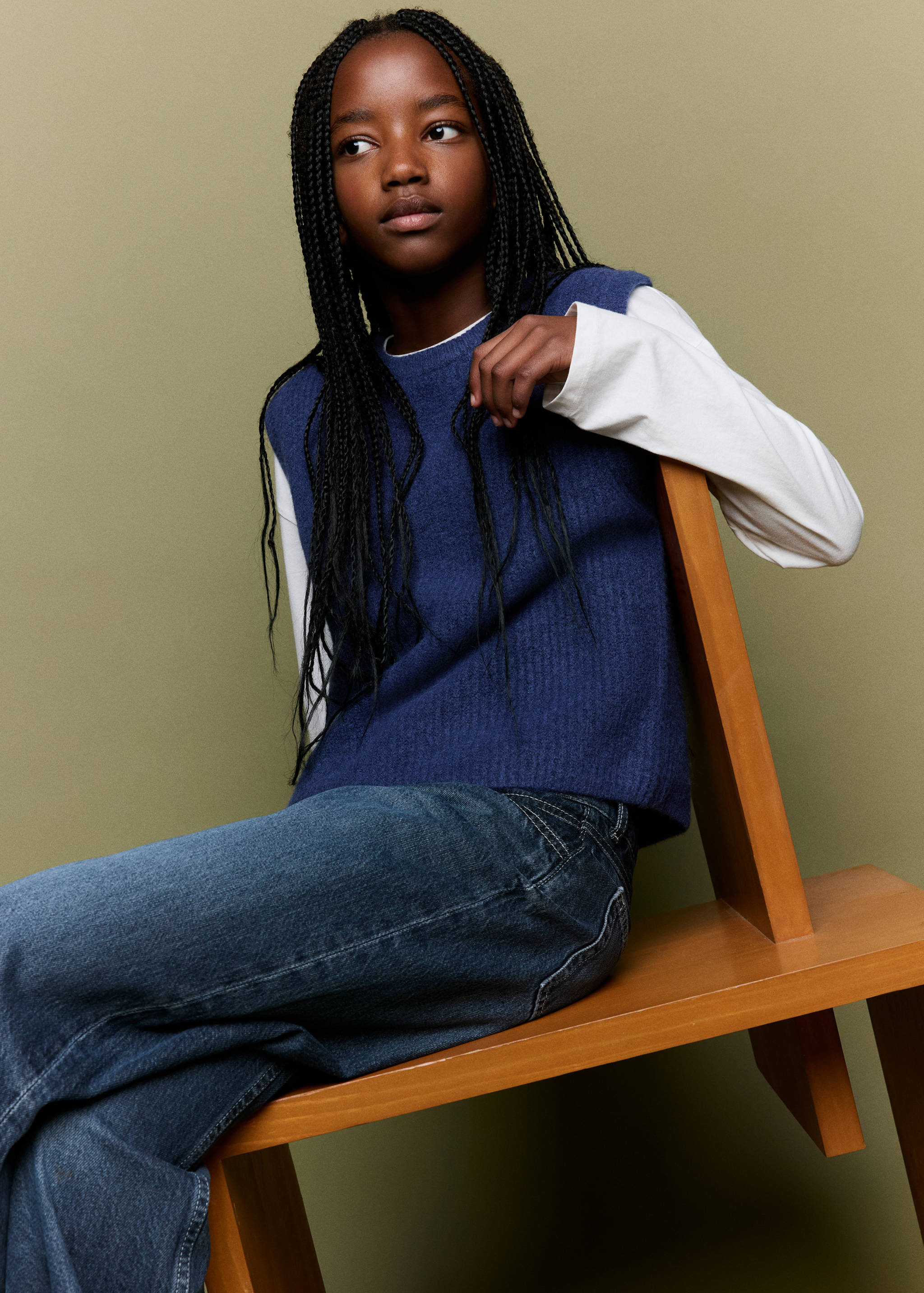 Blue knitted vest with a ribbed texture worn over a white top.