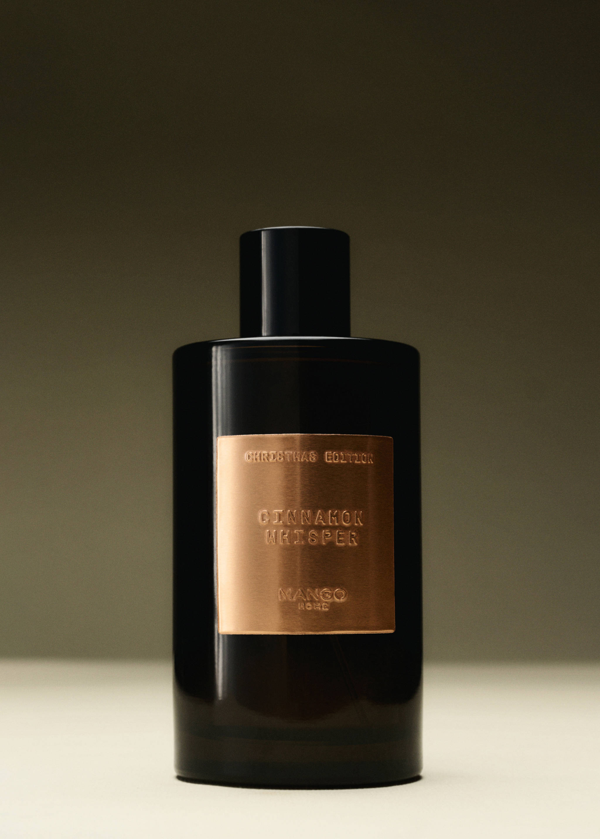 Dark brown glass home spray bottle with a metallic gold label and black cap.
