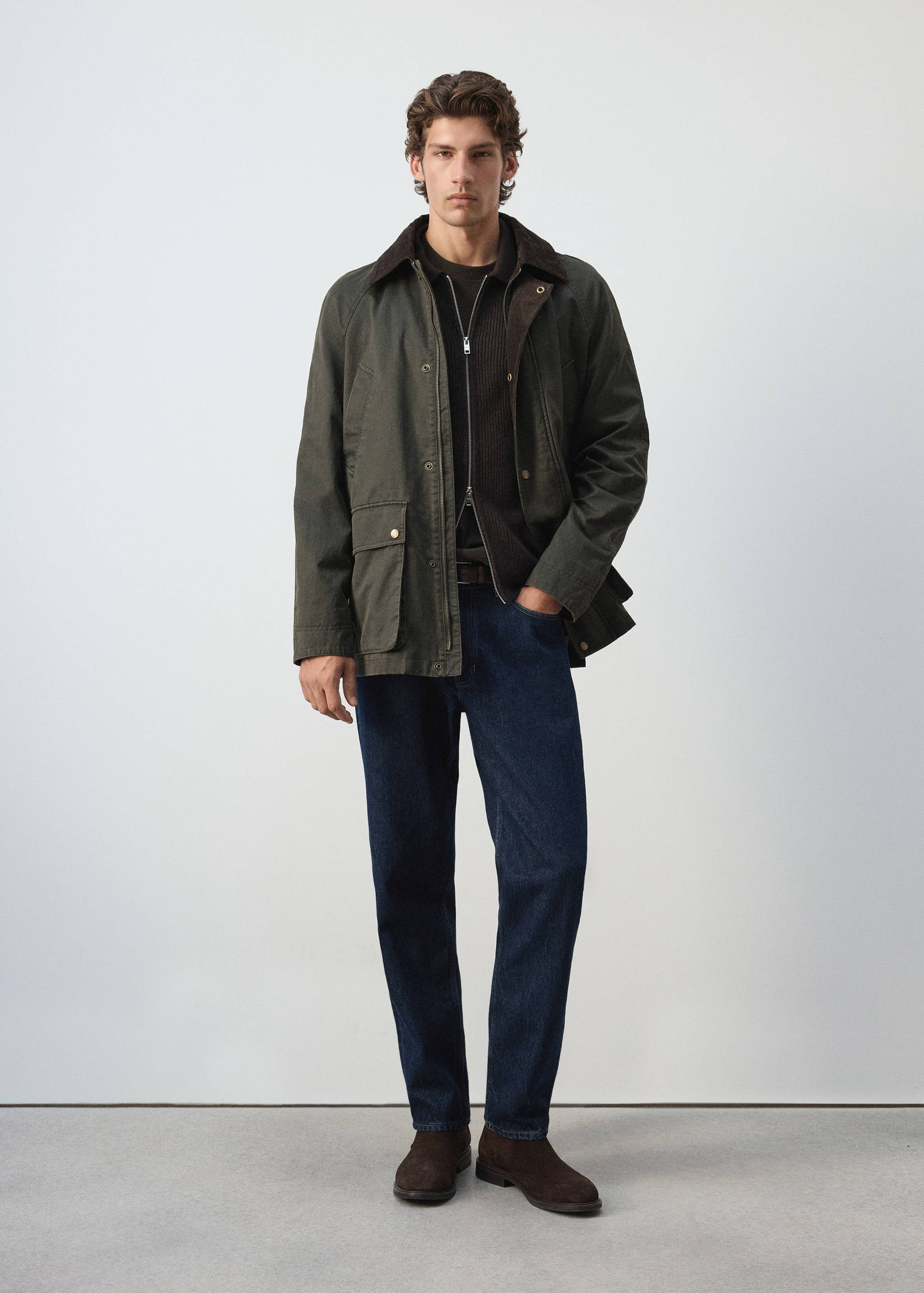 Dark olive-green parka with a brown corduroy collar, worn over a dark brown knit top and blue jeans.