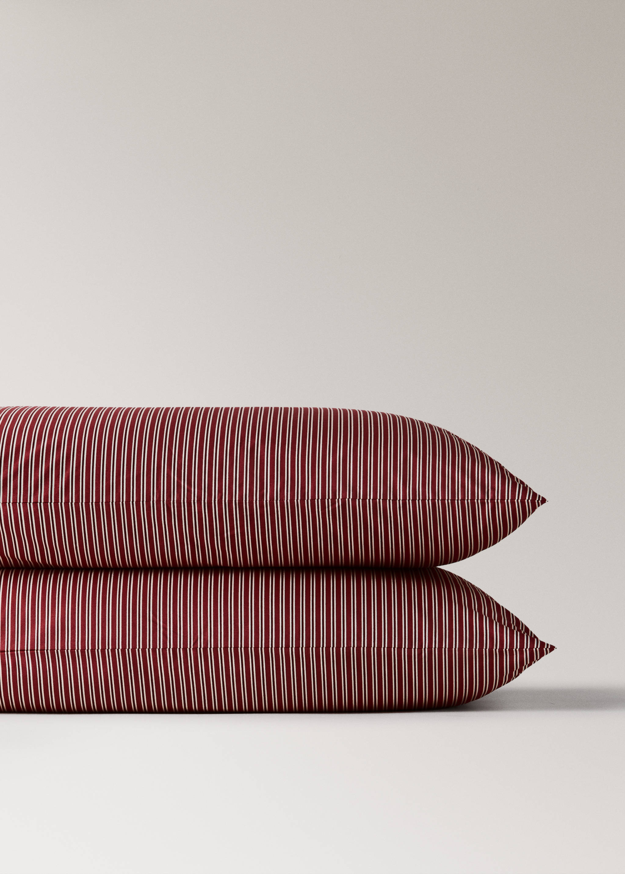 Close-up of two stacked red and white pinstriped pillowcases.