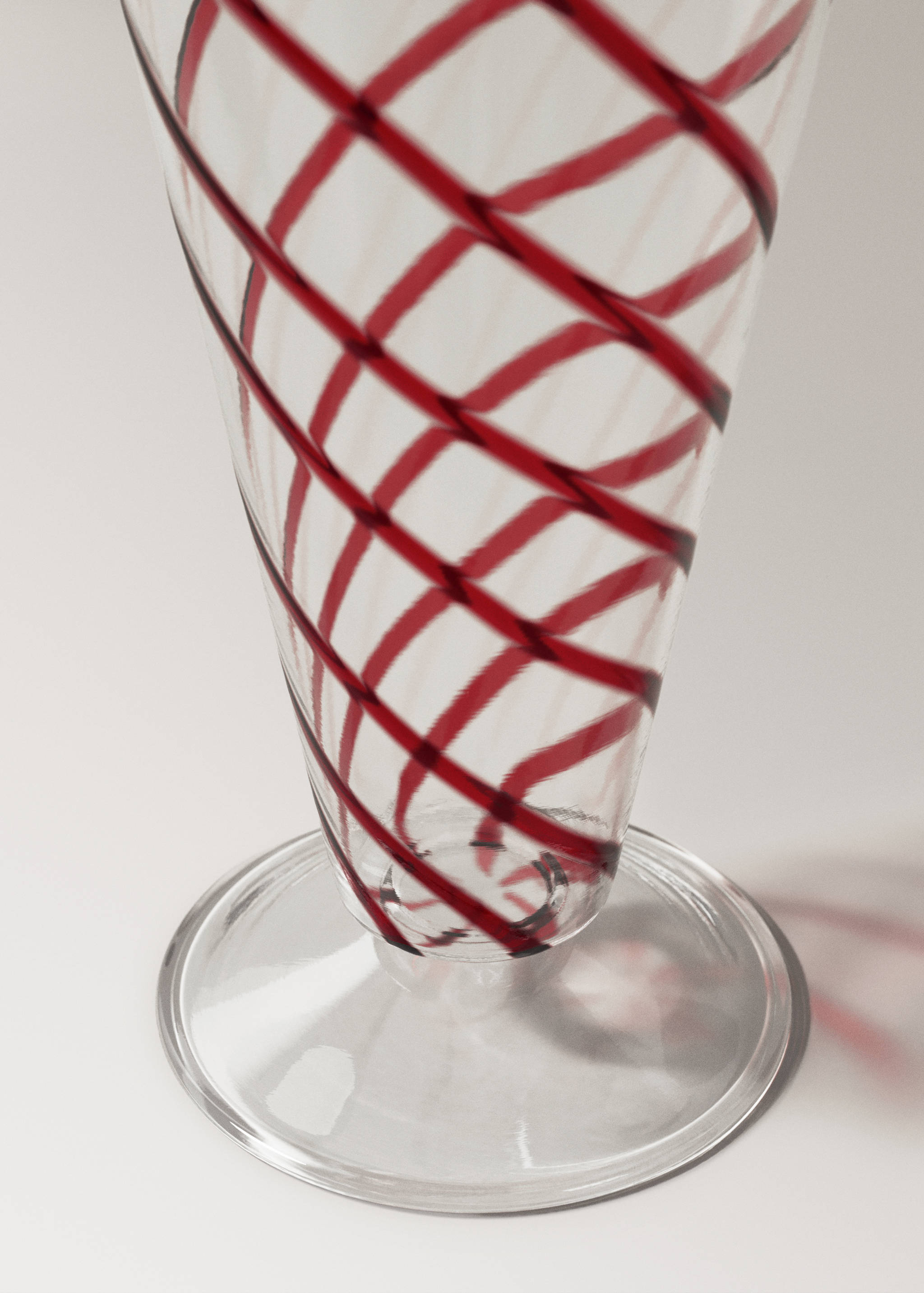 Close-up of a clear glass goblet with red spiral stripes.