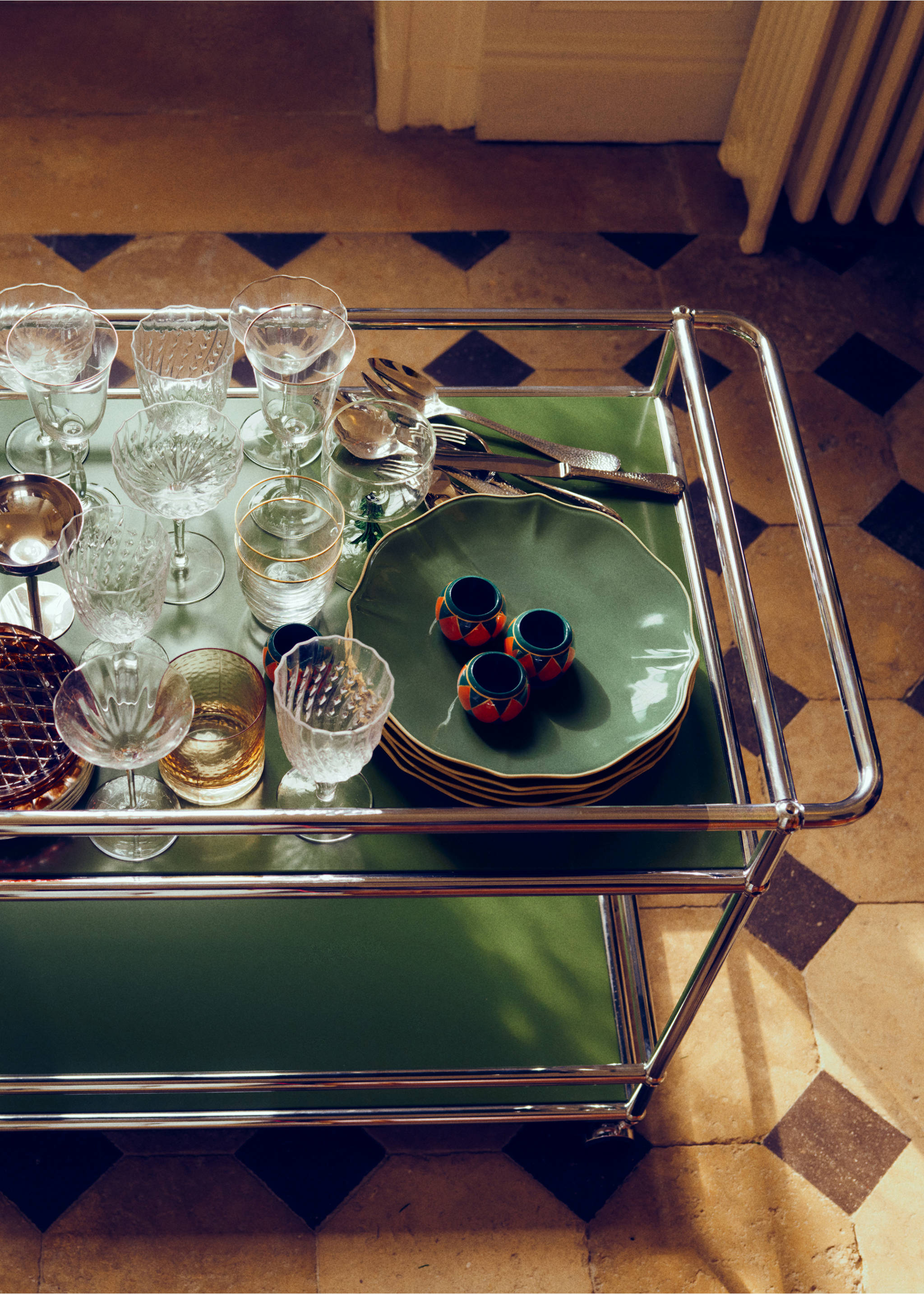Round dark napkin rings with colourful geometric patterns on a green bar cart., Forest Green. Ref: 37077893-00.