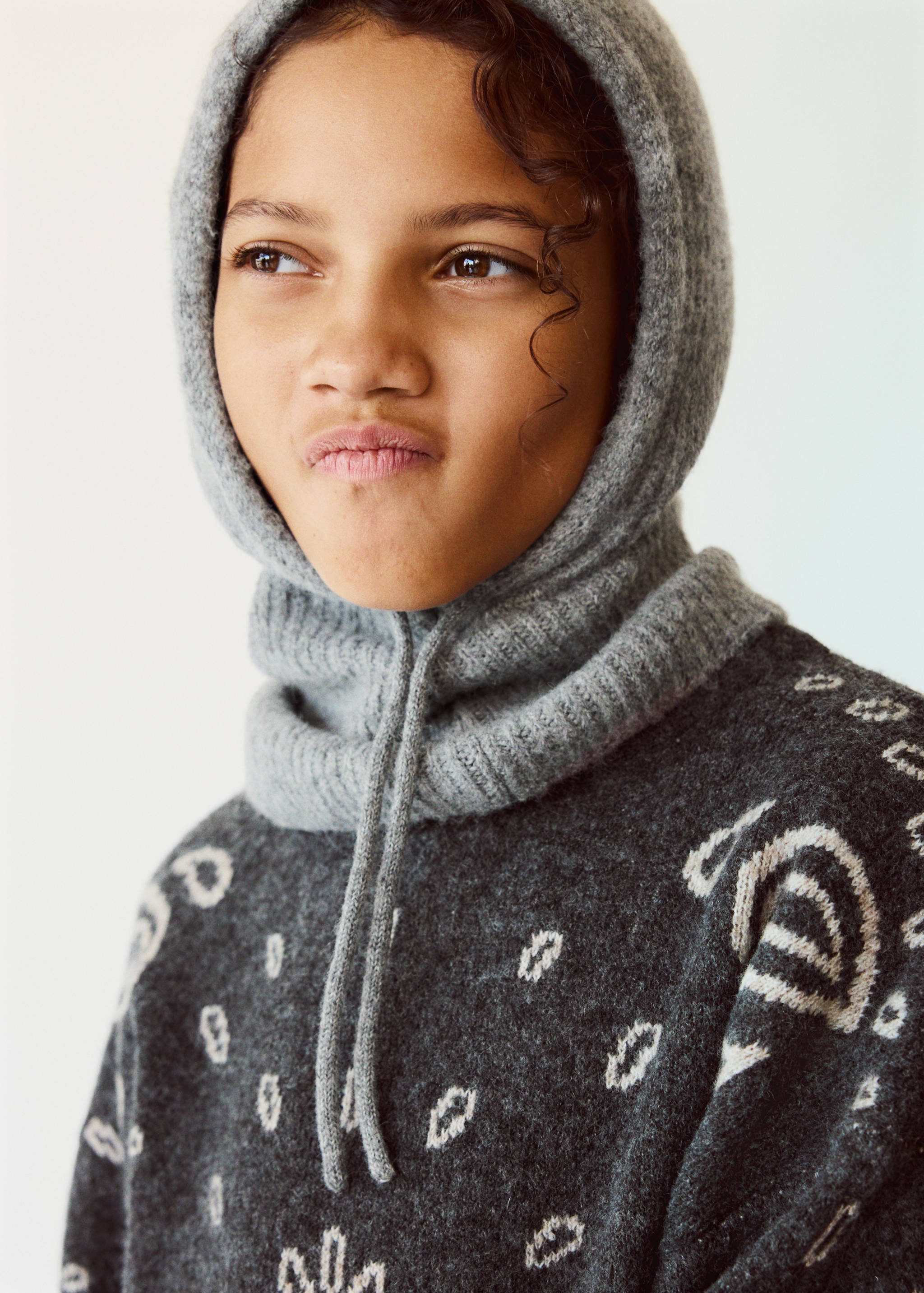 Grey knitted balaclava with a ribbed collar and drawstring ties.