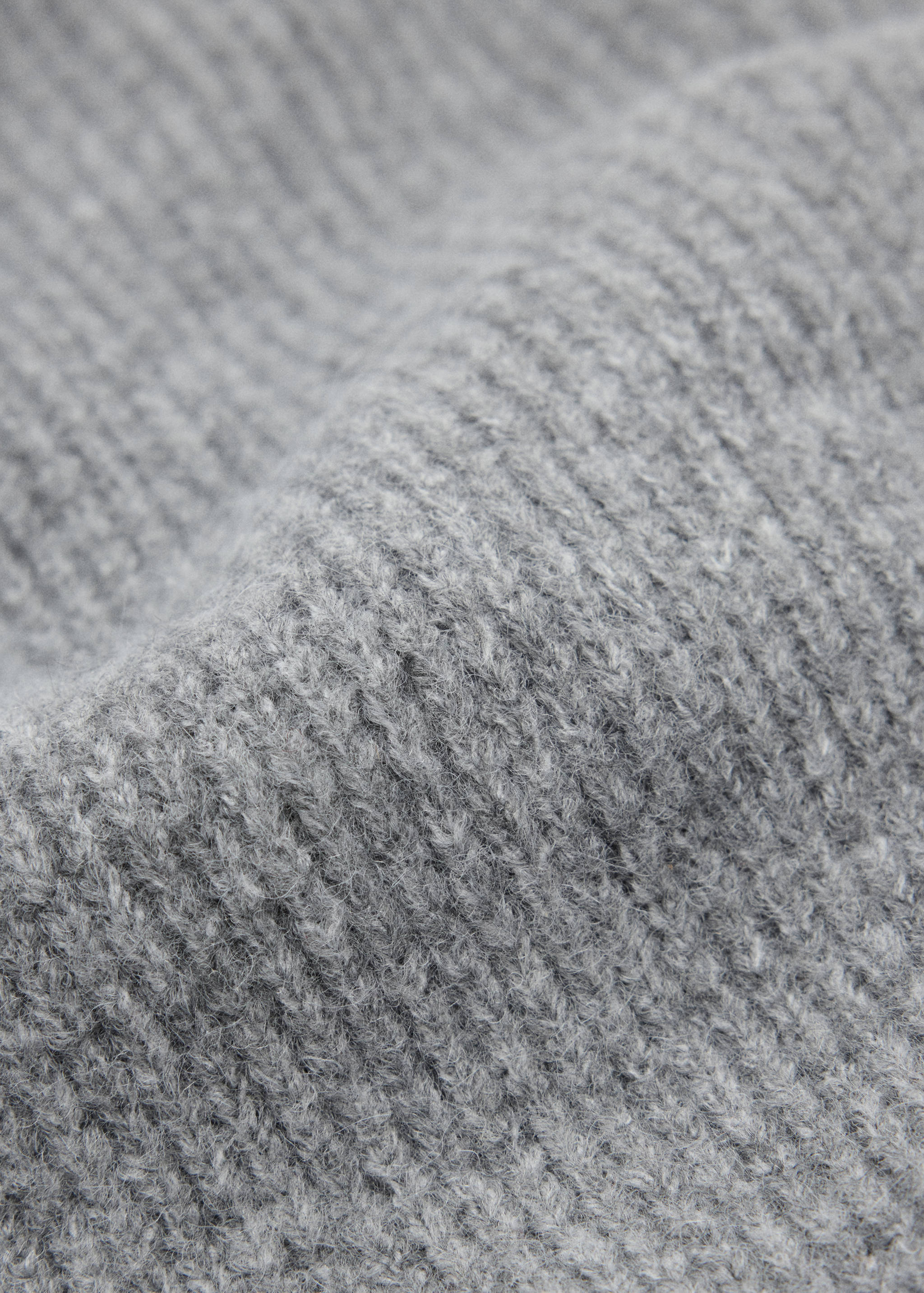 Close-up of a grey ribbed knit beanie showing the textured yarn.