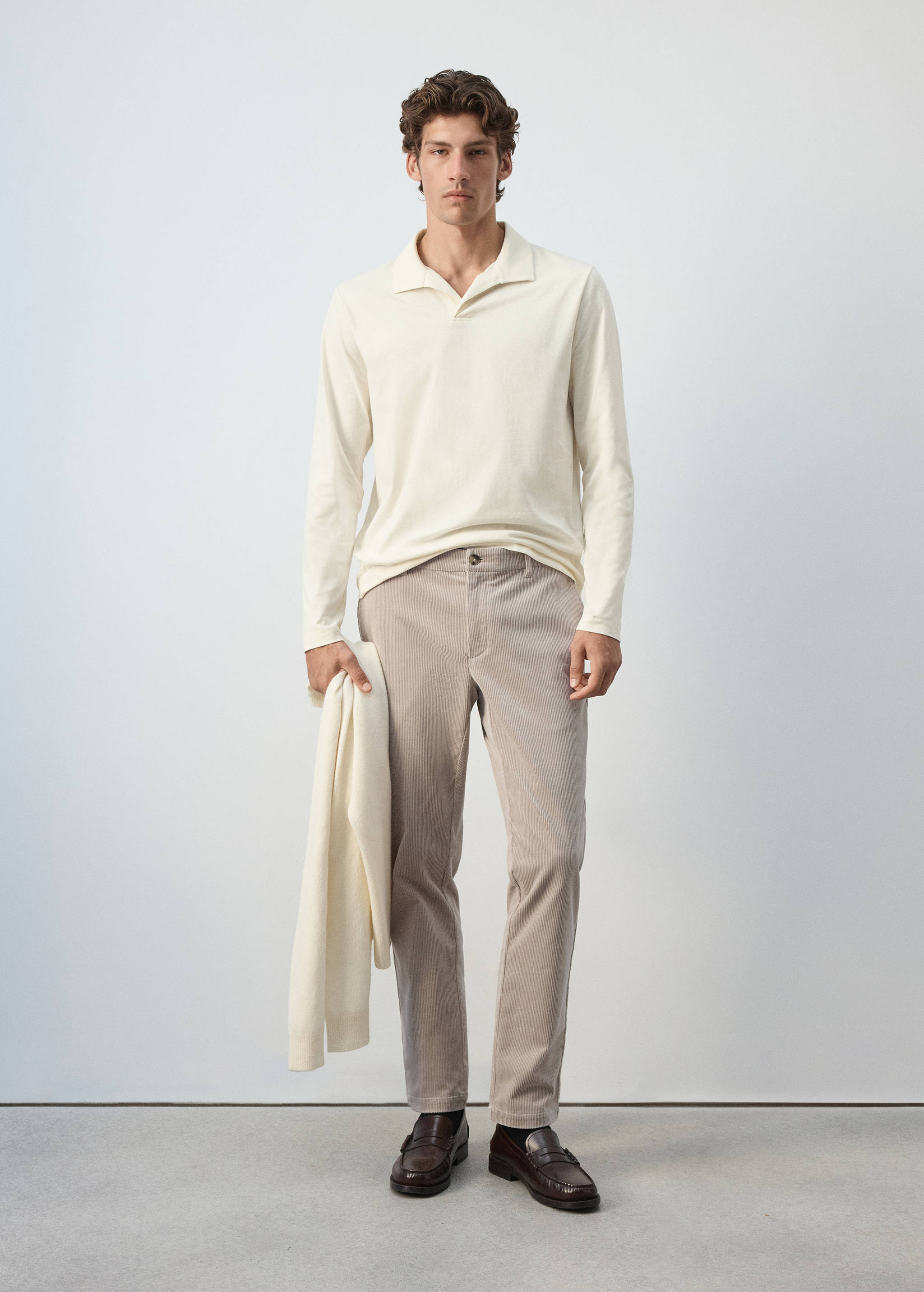 Beige trousers styled with a cream long-sleeved polo shirt.
