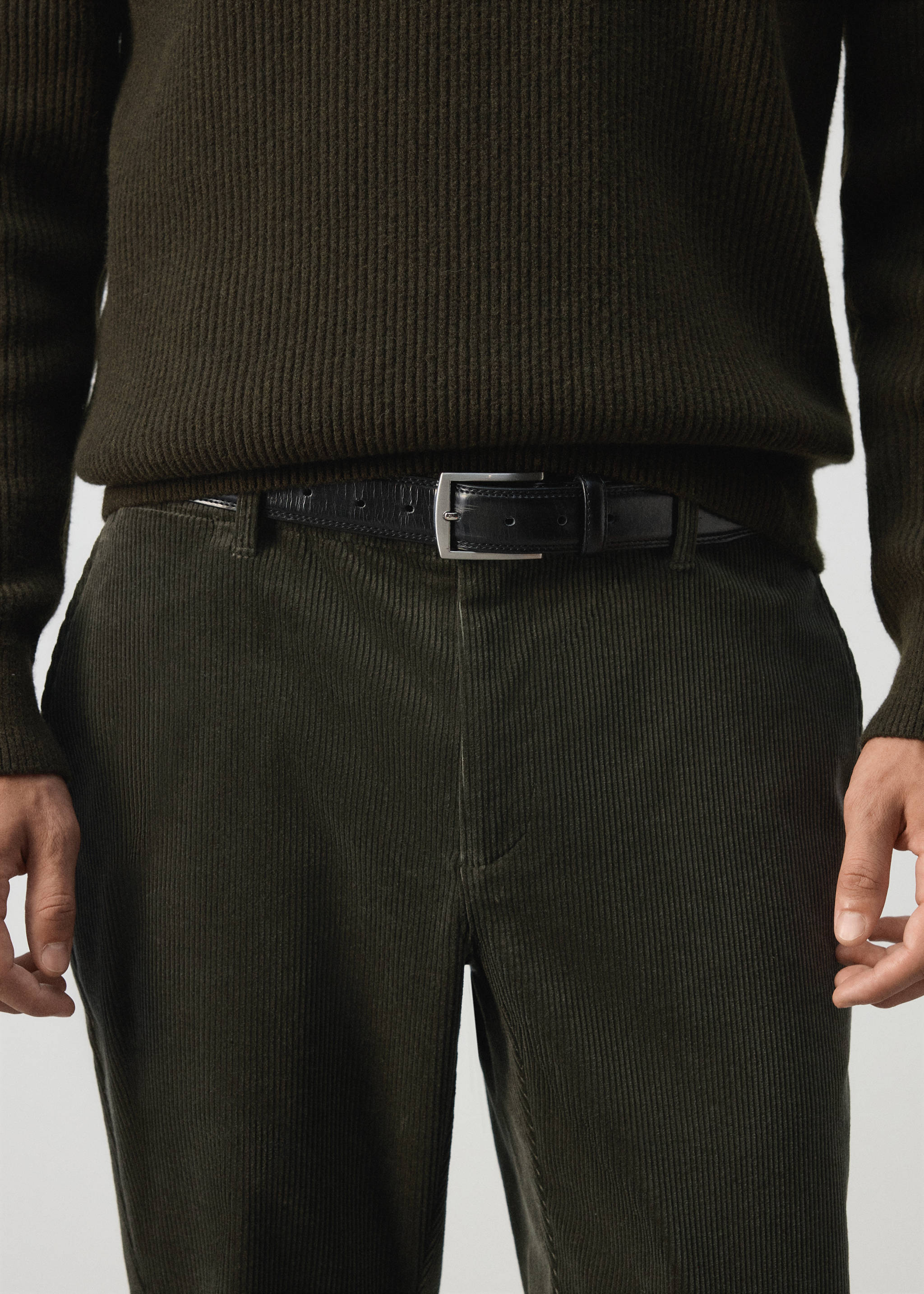 Dark green corduroy trousers worn with a black leather belt.