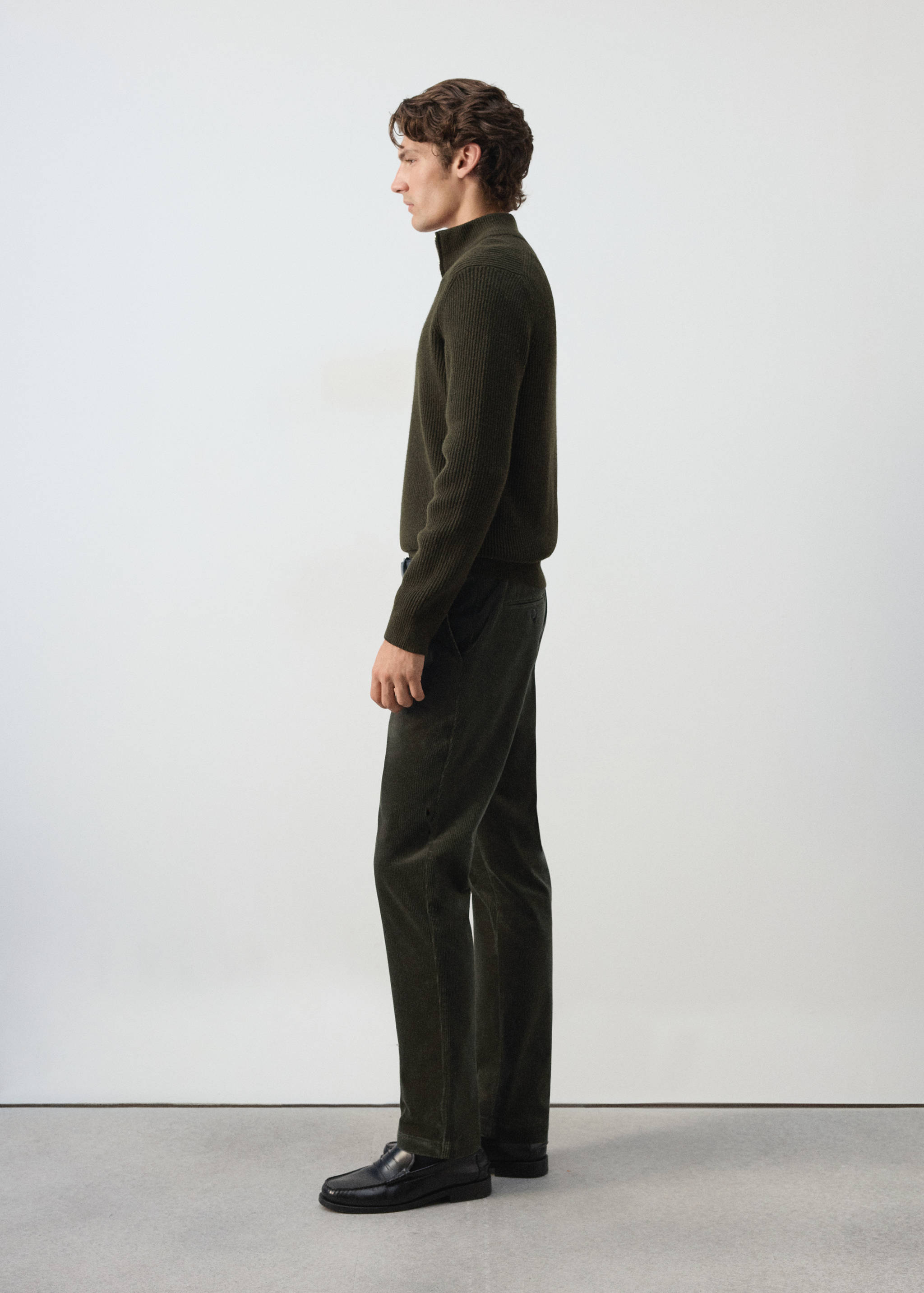 Dark green trousers in a straight-leg fit, shown in profile on a model.