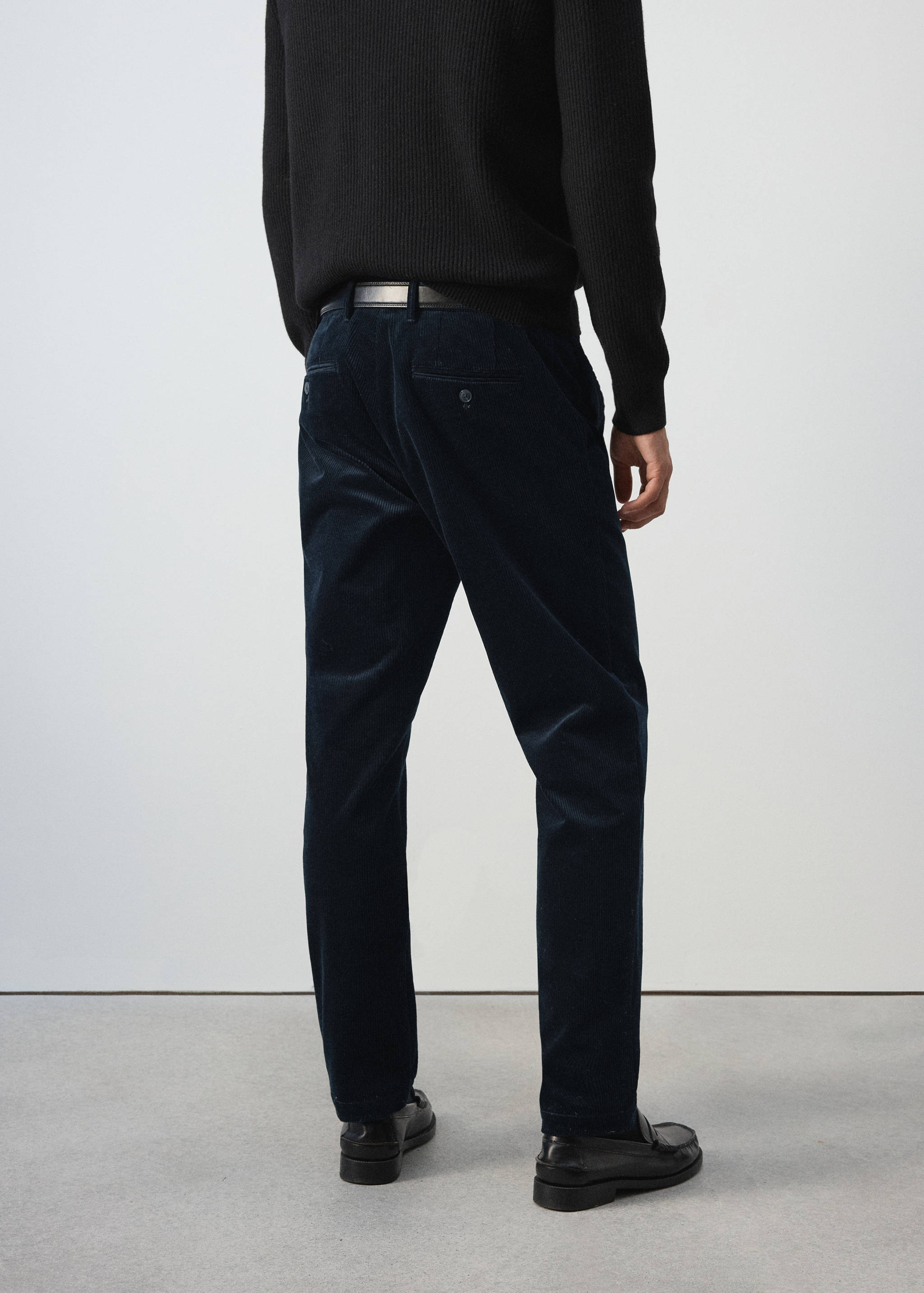 Navy blue corduroy trousers seen from the back on a model.