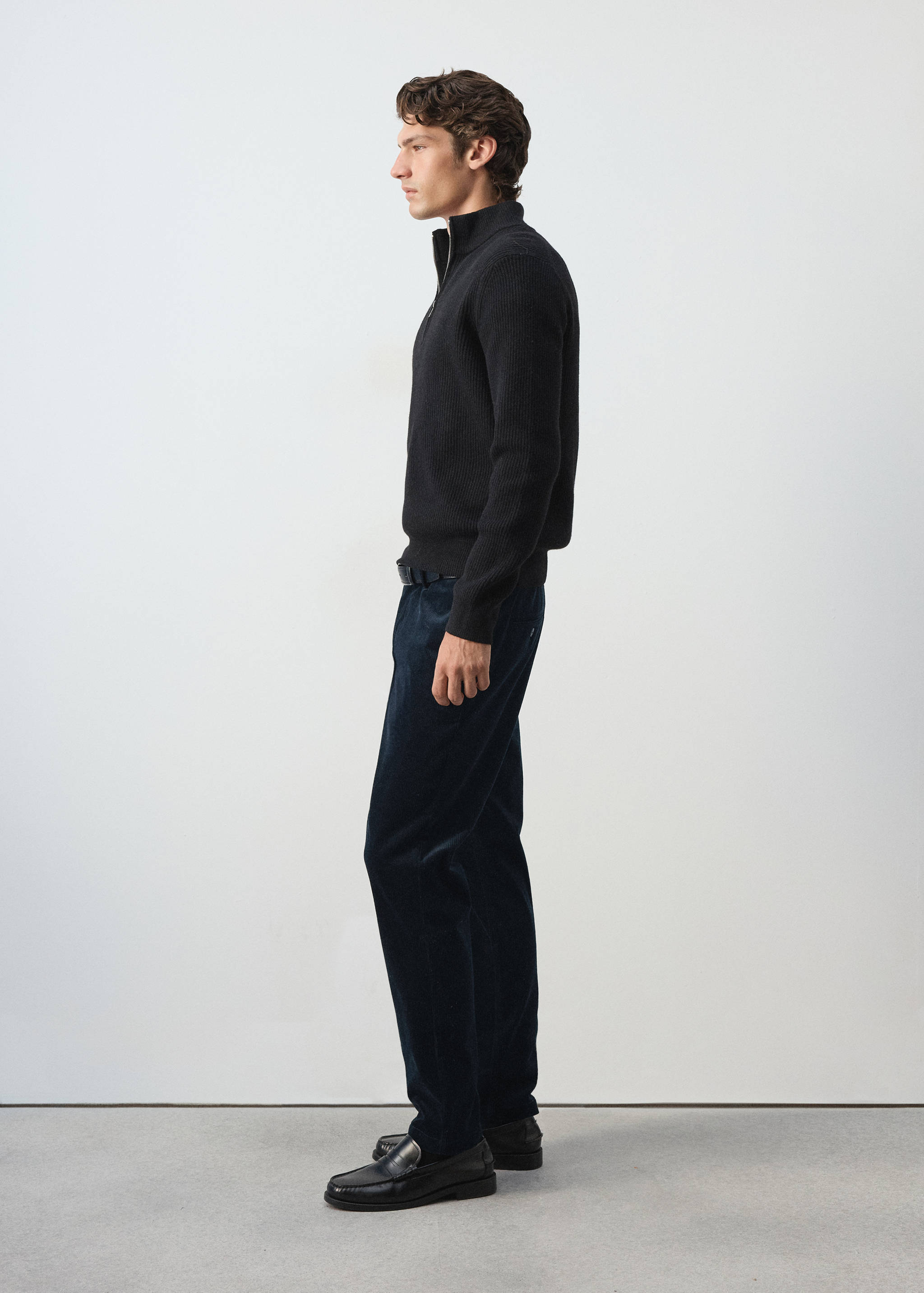 Navy blue corduroy trousers with a straight leg, worn with a black zip-neck jumper.