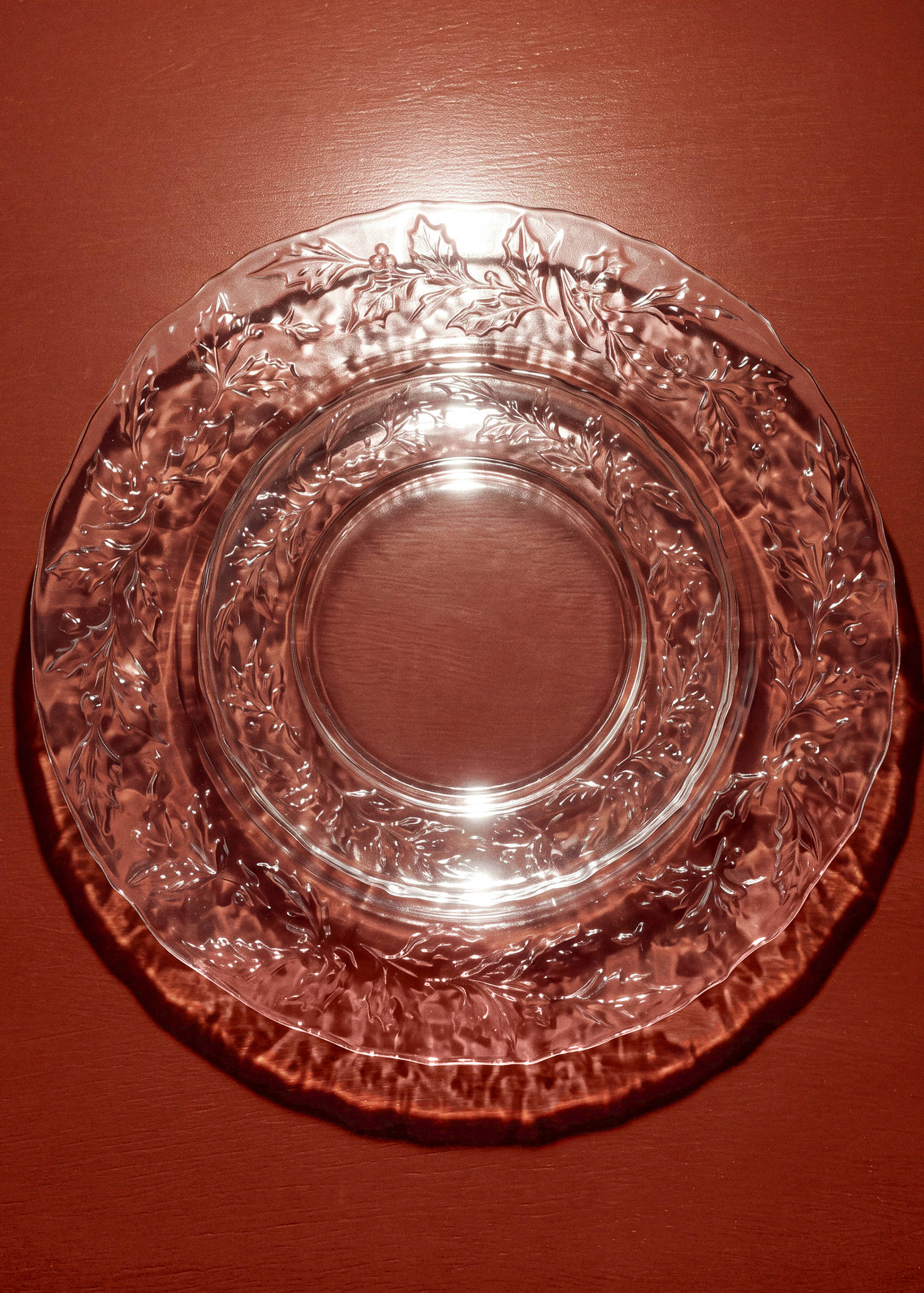 Clear glass plate with embossed holly leaf pattern and scalloped rim.