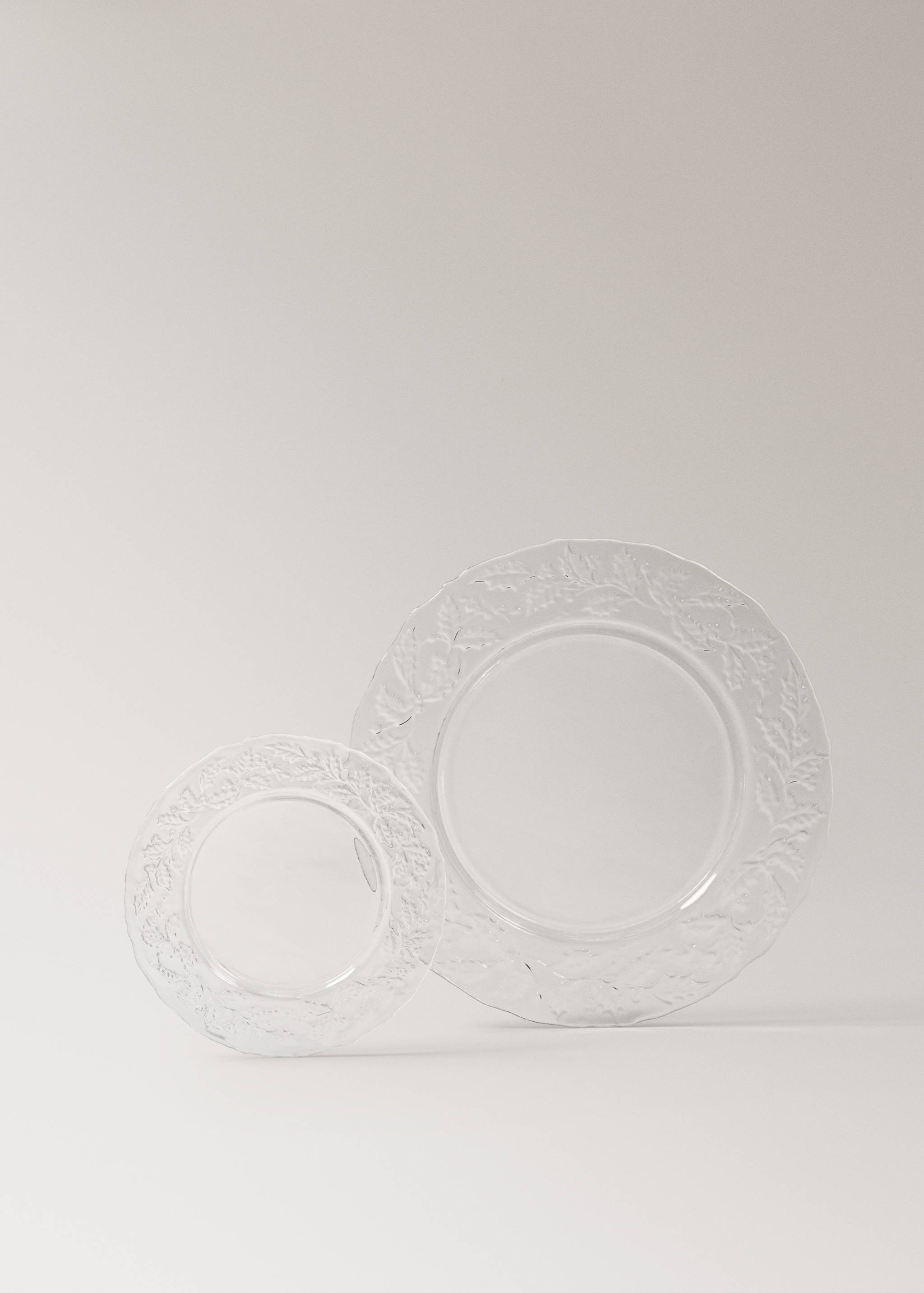 Two clear glass plates with textured leaf and berry rims.