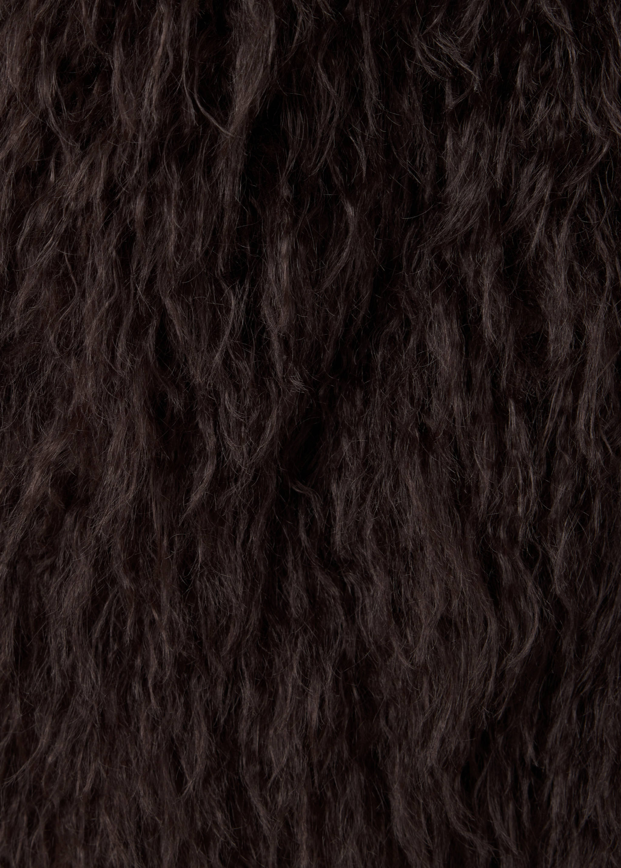 Close-up of dark brown shaggy faux-fur waistcoat fabric.