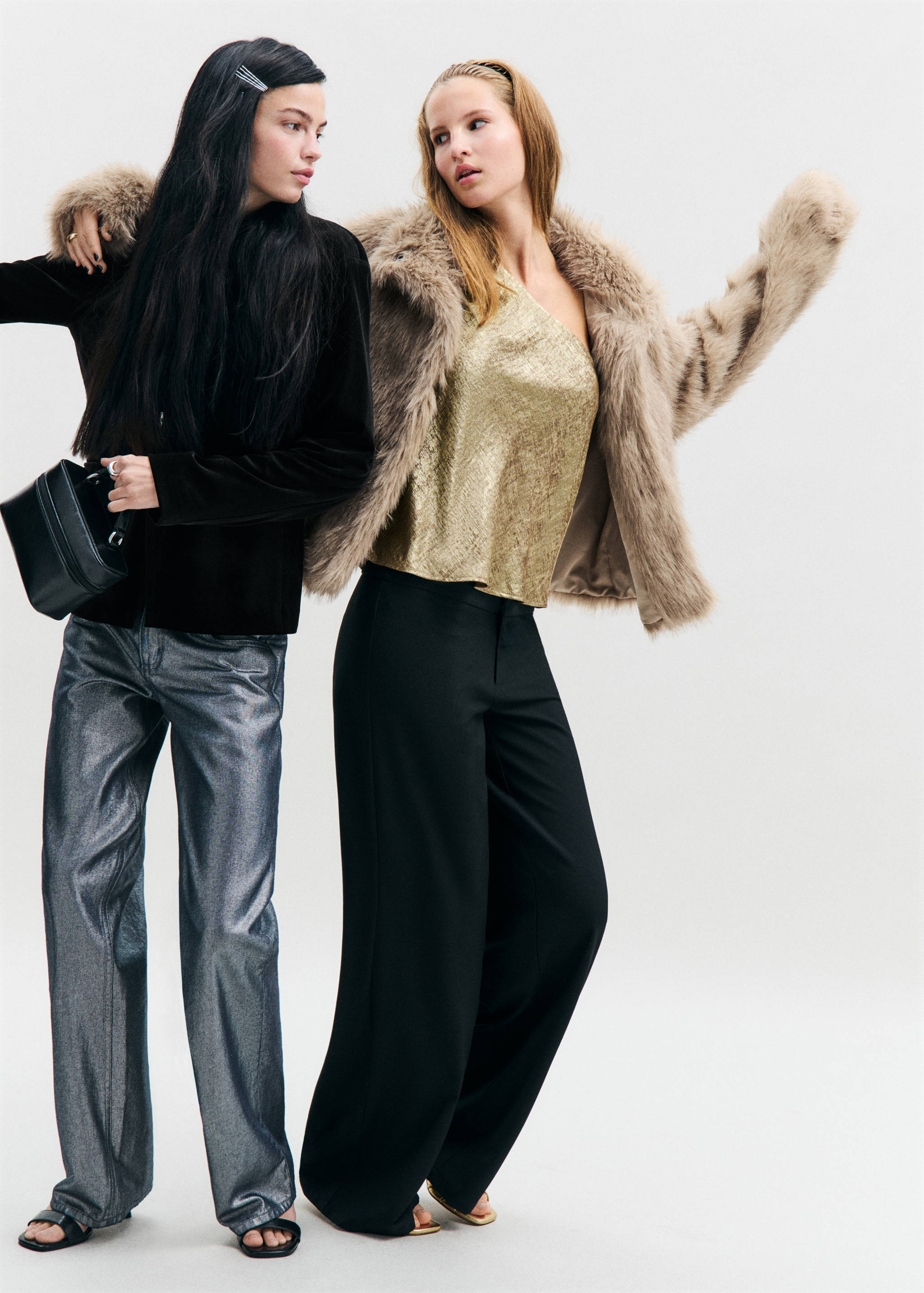 Beige faux-fur coat worn with a gold one-shoulder top and black trousers.