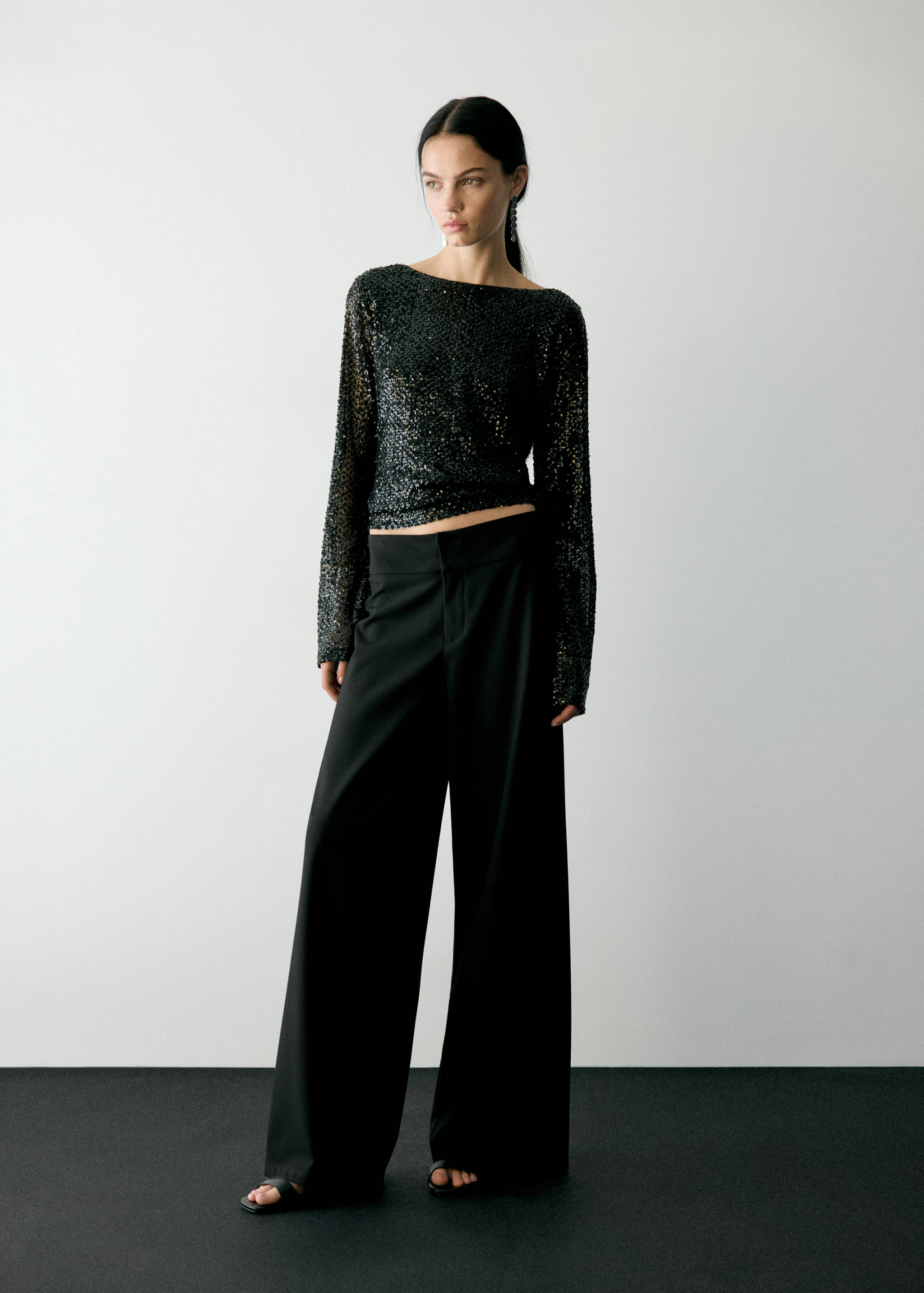 Black wide-leg trousers worn with a sparkling sequin top.