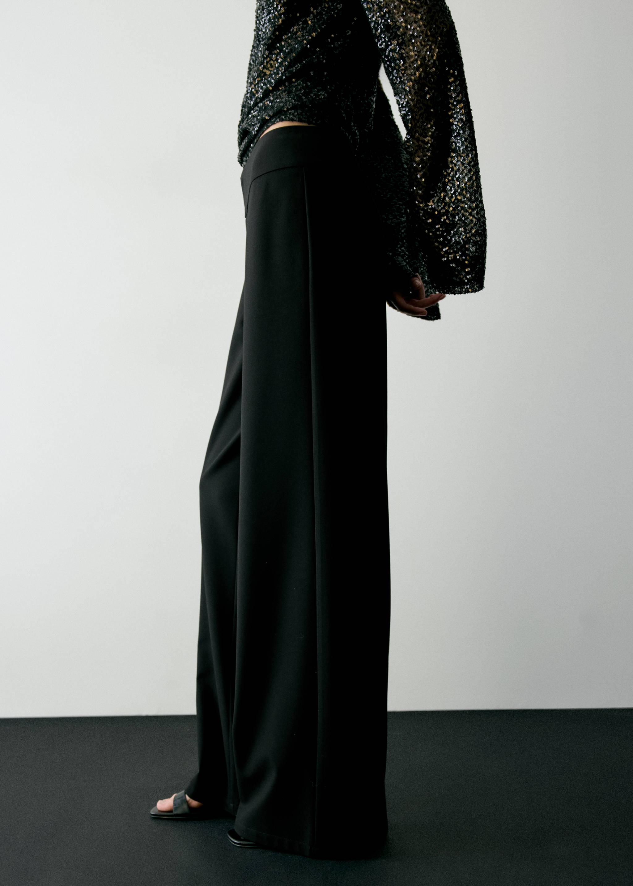 Black wide-leg trousers with a high-rise waist and flowing silhouette.