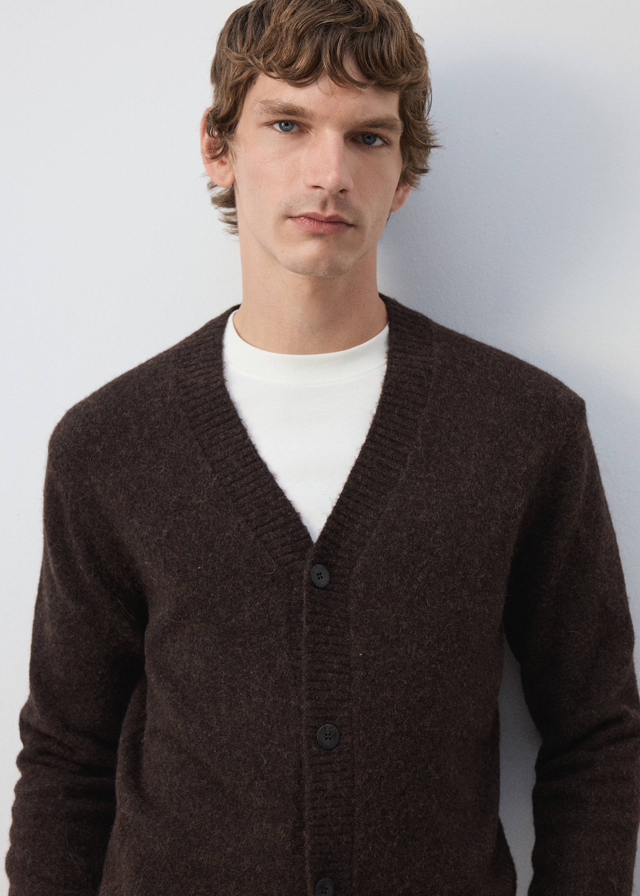 Dark brown V-neck knitted cardigan worn over a white t-shirt.