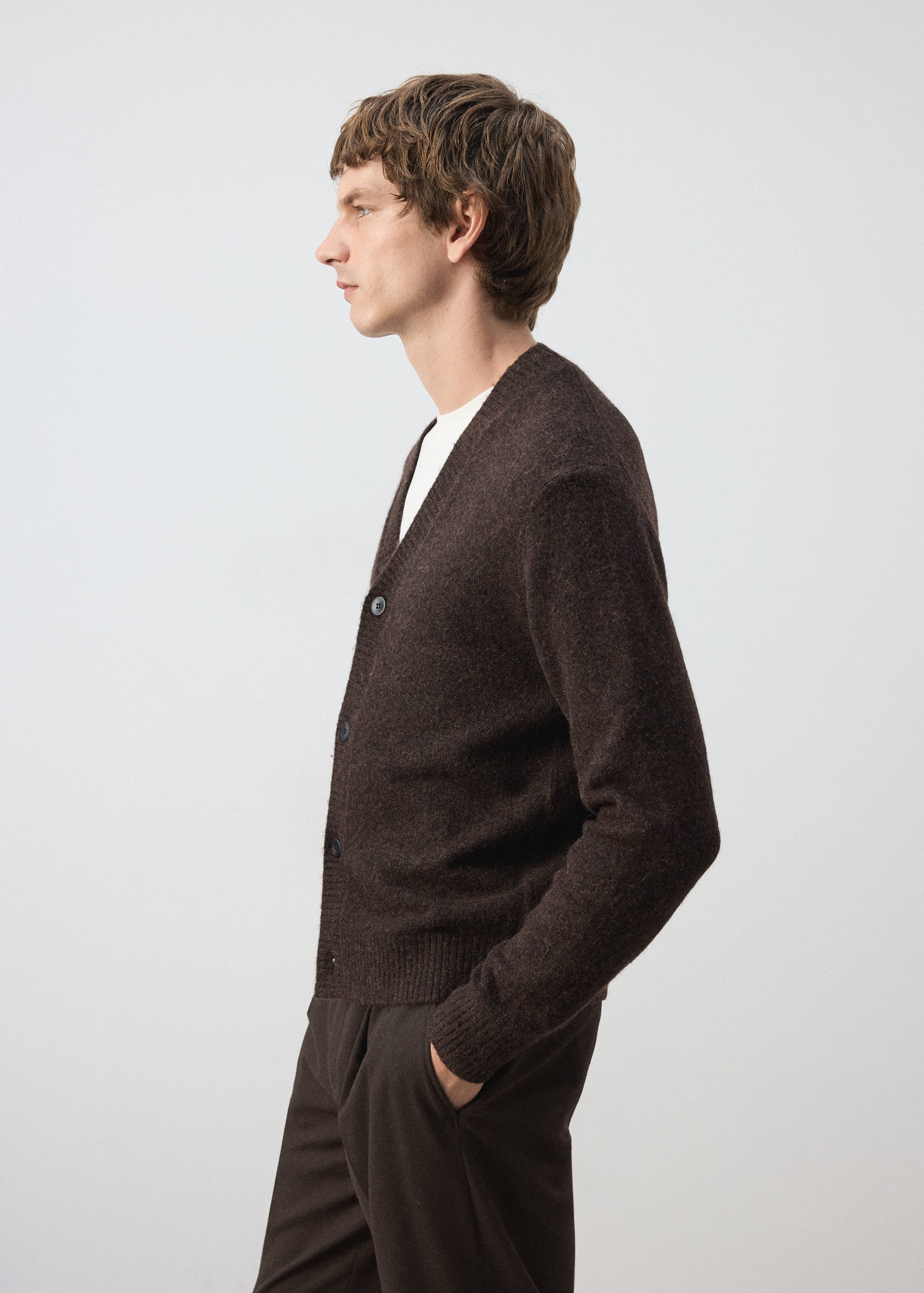 Dark brown knitted V-neck cardigan worn over a white t-shirt.