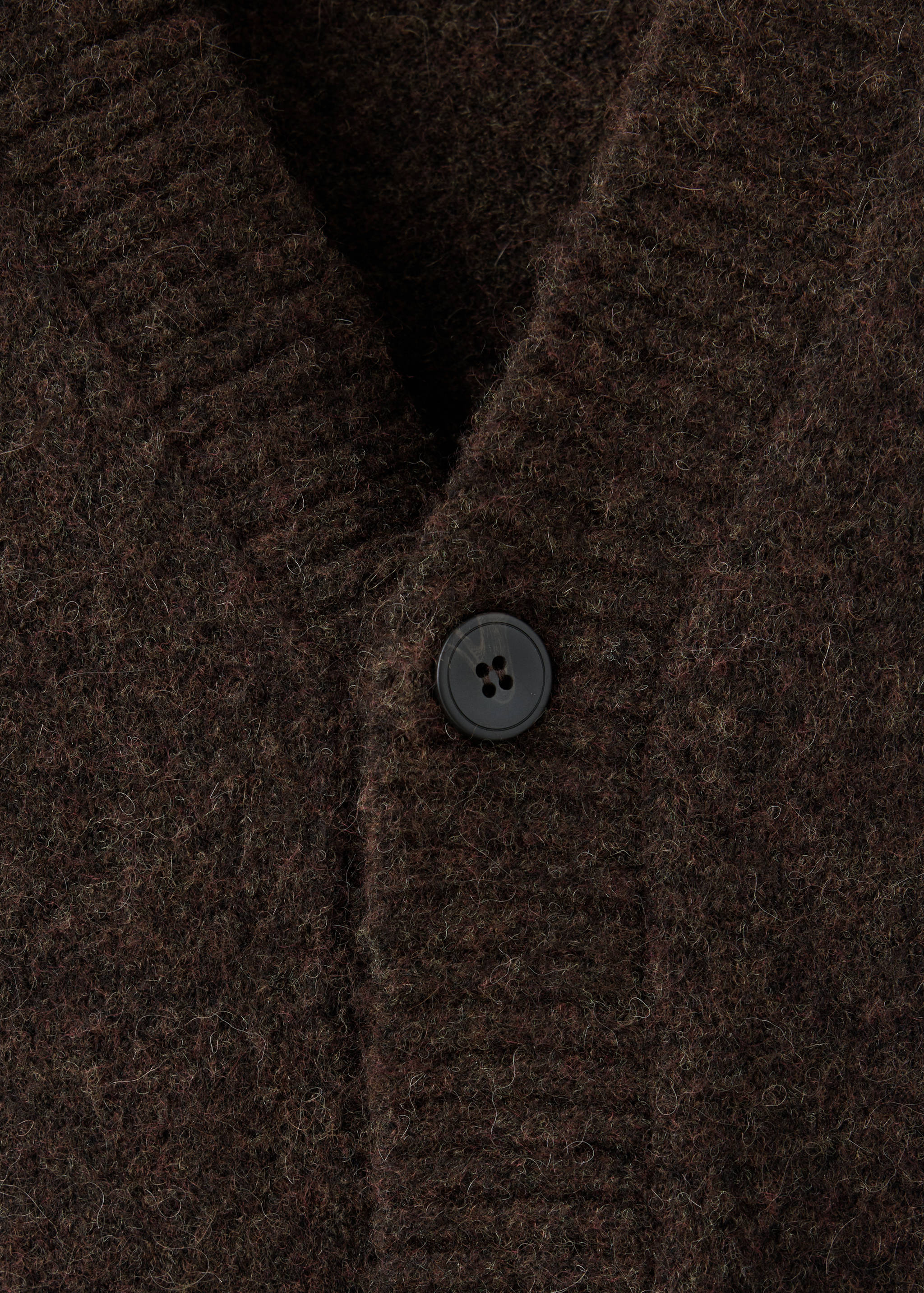 Close-up of a brown knitted cardigan with a V-neck and button detail.